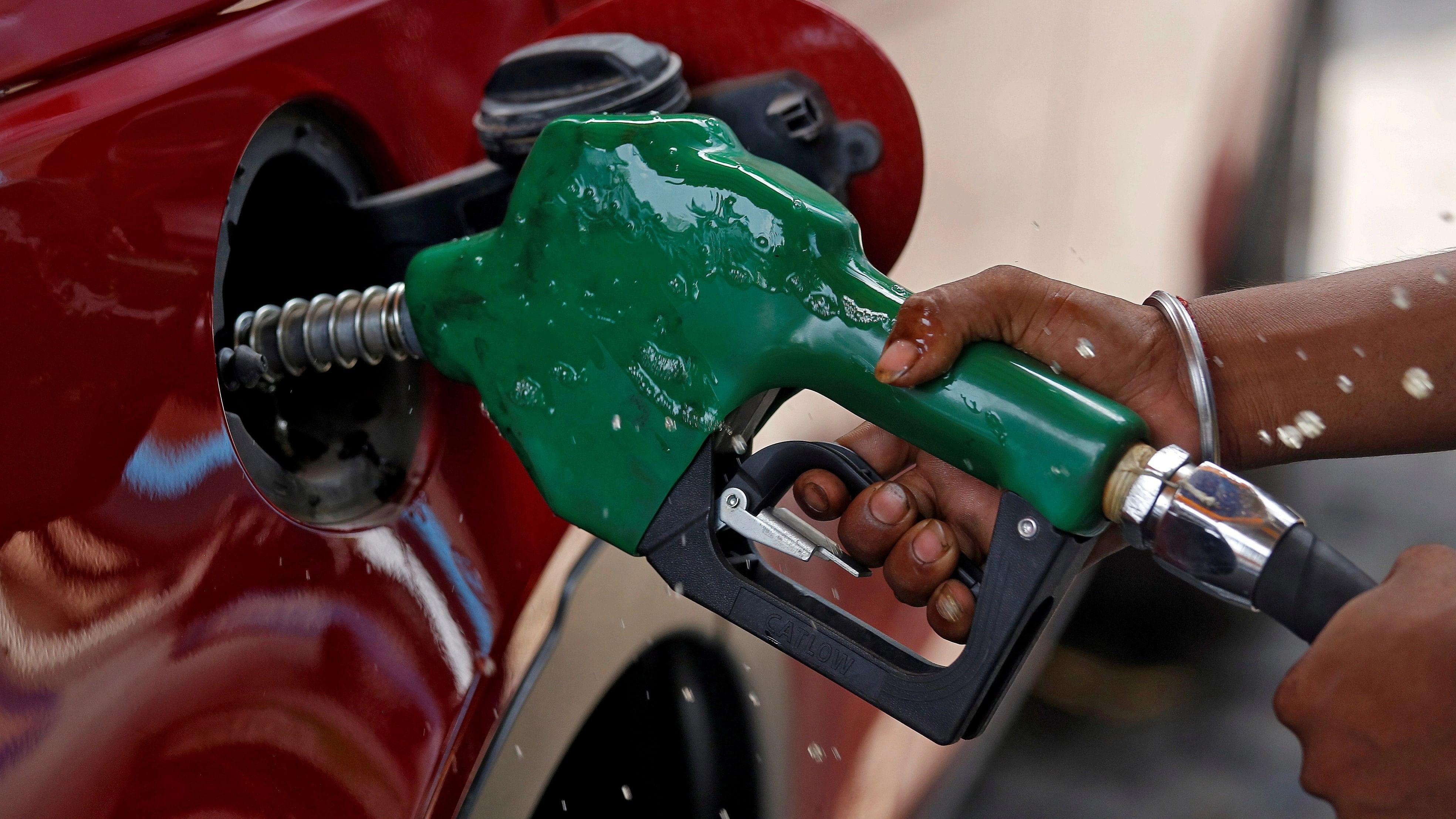 <div class="paragraphs"><p>A worker holds a nozzle to pump petrol into a vehicle at a fuel station</p></div>