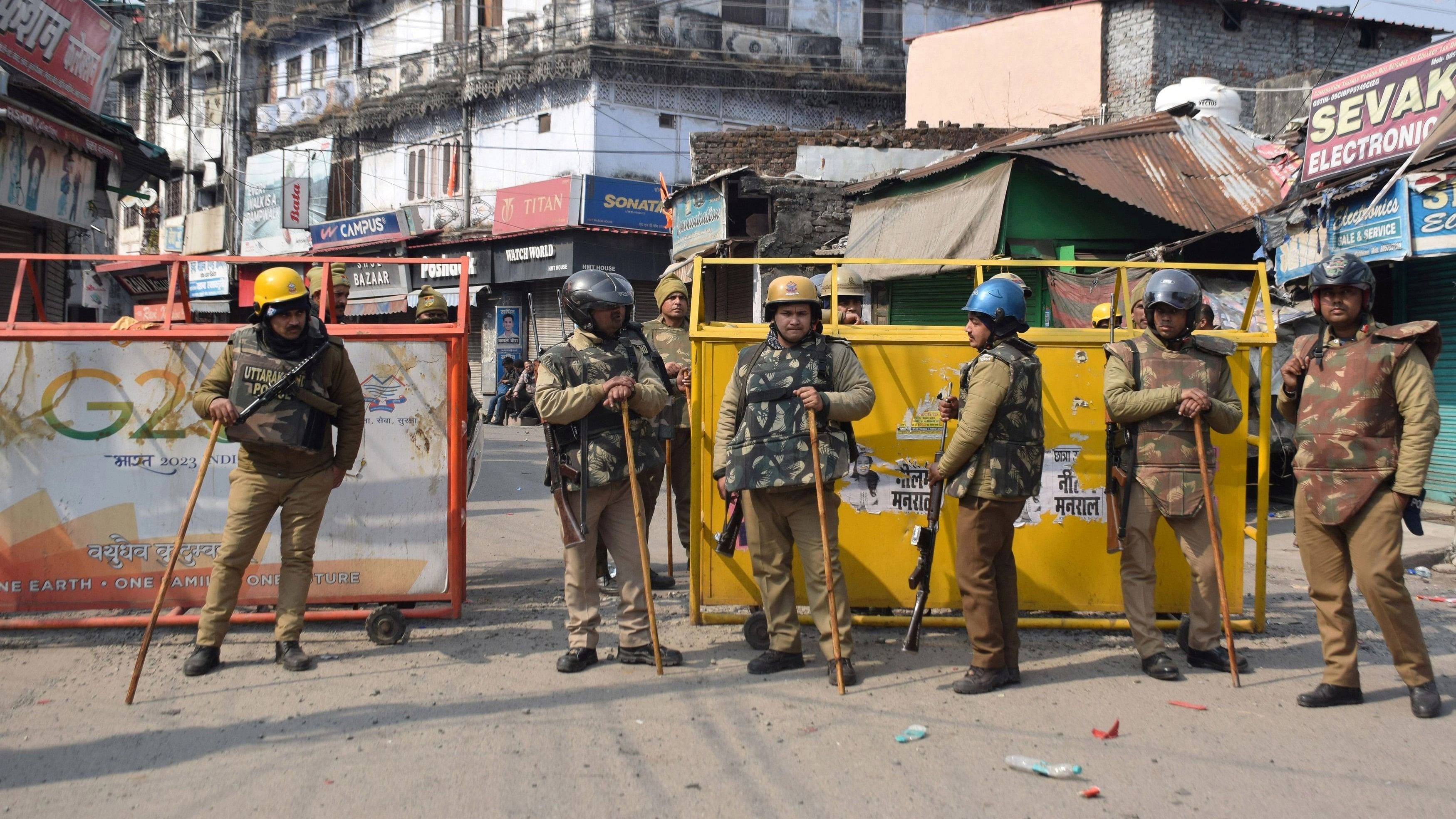 <div class="paragraphs"><p>Police officers in riot gear stand guard next to a barricade on a road a day after clashes during a government demolition drive in Haldwani.</p></div>