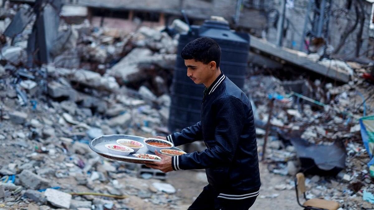 <div class="paragraphs"><p>A member of Palestinian Abu Ghouta family carries a tray with food as he prepares to break his fast near the rubble of their destroyed house during the holy month of Ramadan, amid the ongoing conflict between Israel and Hamas, in Rafah in the southern Gaza Strip.</p></div>