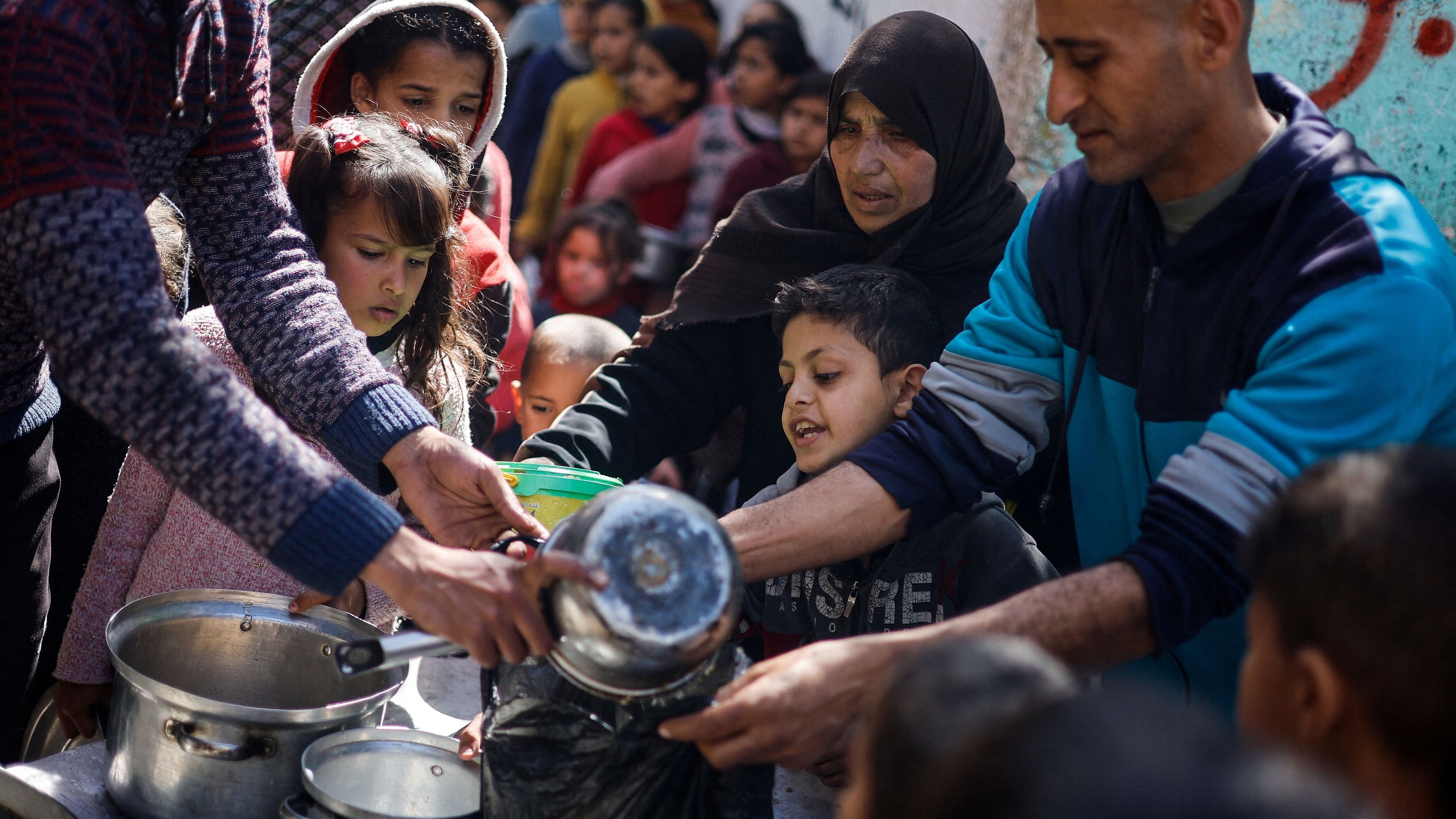 <div class="paragraphs"><p>Palestinian children wait to receive food cooked by a charity kitchen amid shortages of food supplies, in Rafah.</p></div>