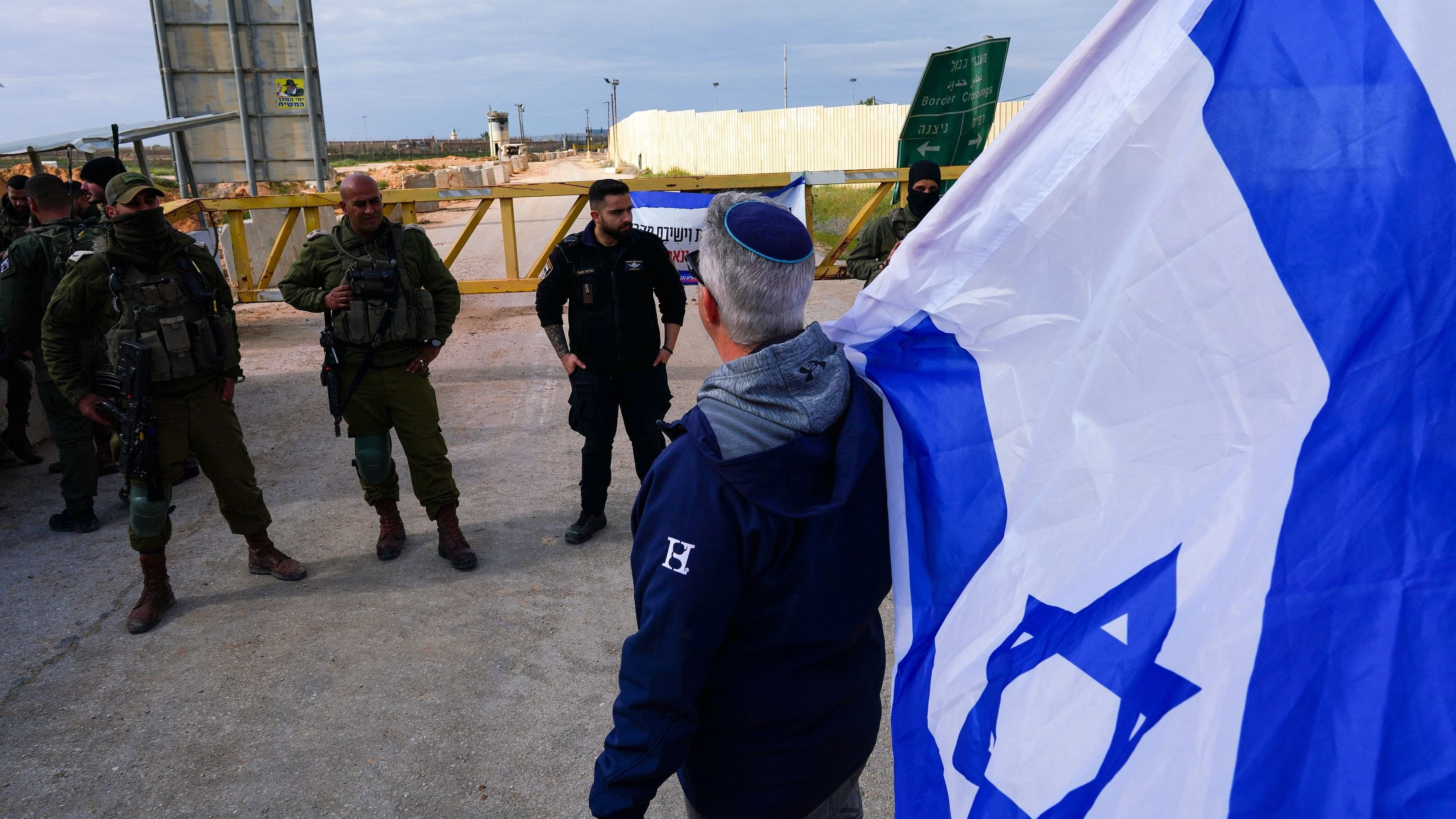 <div class="paragraphs"><p>A demonstrator holding an Israeli flag stands next to Israeli security officials.</p></div>