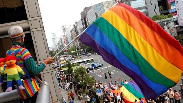 <div class="paragraphs"><p>A participant holds a rainbow flag on a balcony during an LGBT Pride parade.</p></div>