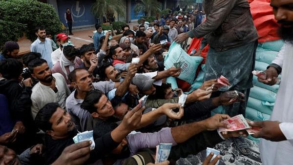 <div class="paragraphs"><p> Men reach out to buy subsidised flour sacks from a truck in Karachi.</p></div>