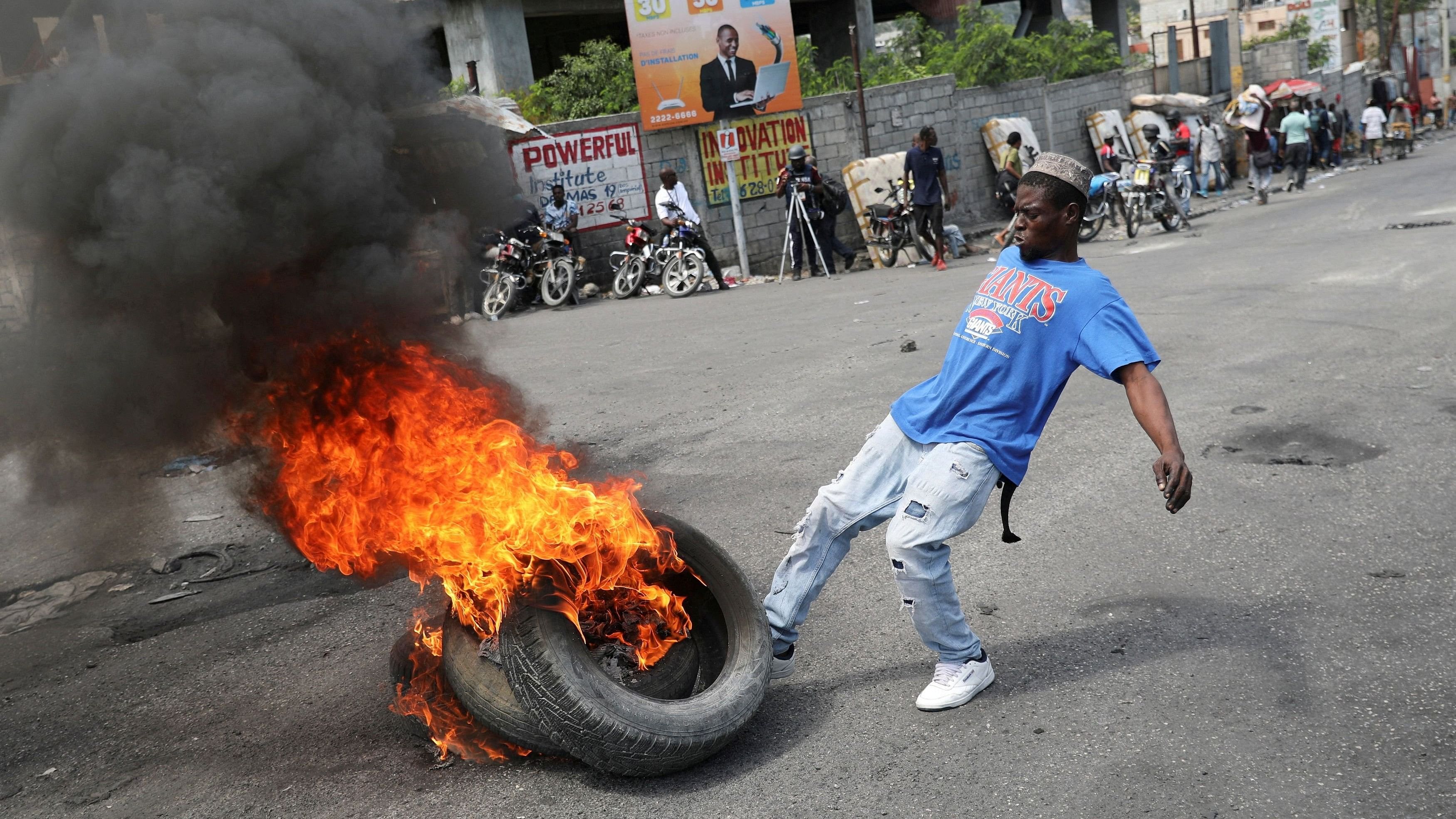 <div class="paragraphs"><p>A man kicks burning tires during a protest as the government said it would extend a state of emergency for another month after an escalation in violence from gangs seeking to oust the Prime Minister Ariel Henry, in Port-au-Prince, Haiti, March 7, 2024. </p></div>
