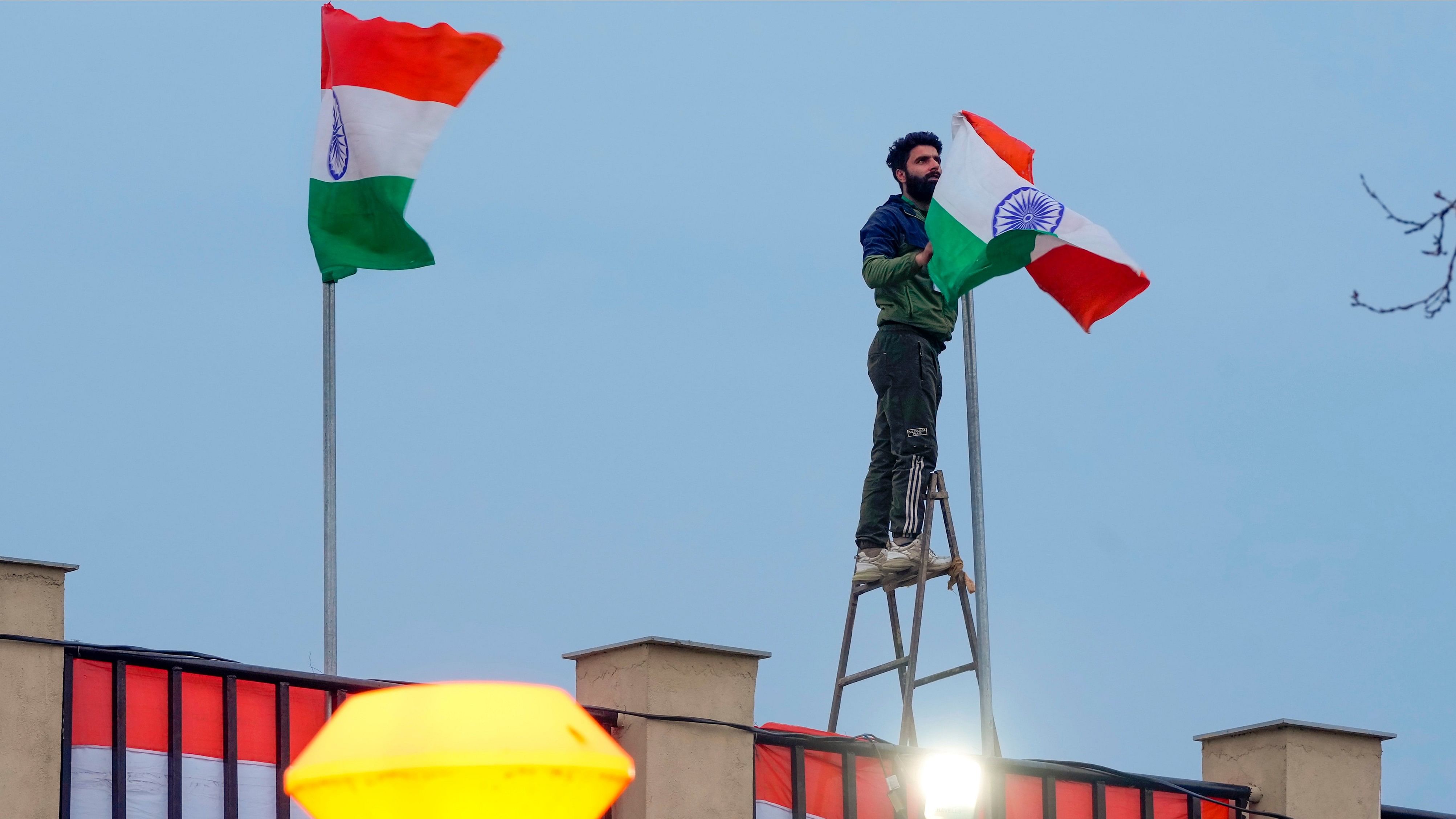 <div class="paragraphs"><p>A worker puts up national flags ahead of Prime Minister Narendra Modi's visit to Kashmir valley in Srinagar.</p></div>