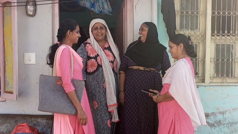 ASHA workers Sunitha Santhosh and M Deepanjali (pink uniform) at Nehru Nagar slum in Mysuru. 