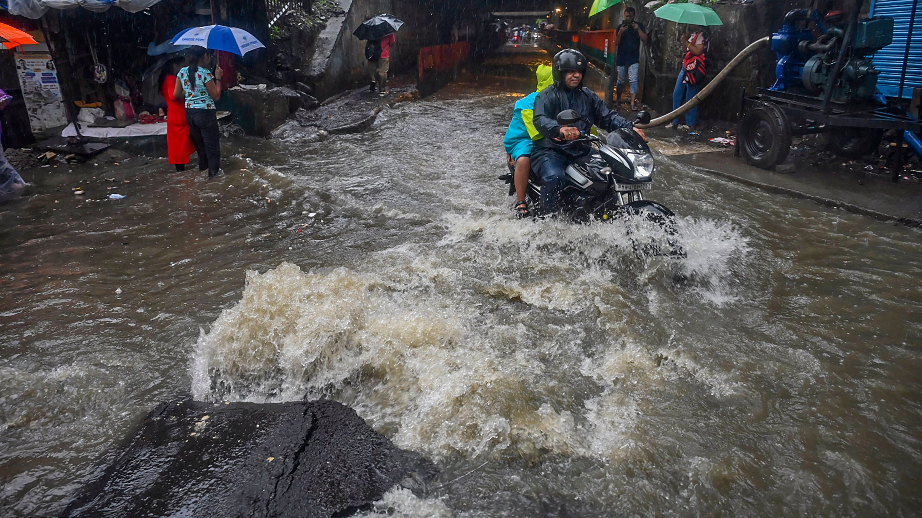 <div class="paragraphs"><p>Commuters on a waterlogged road amid rain in Mumbai last year.</p></div>