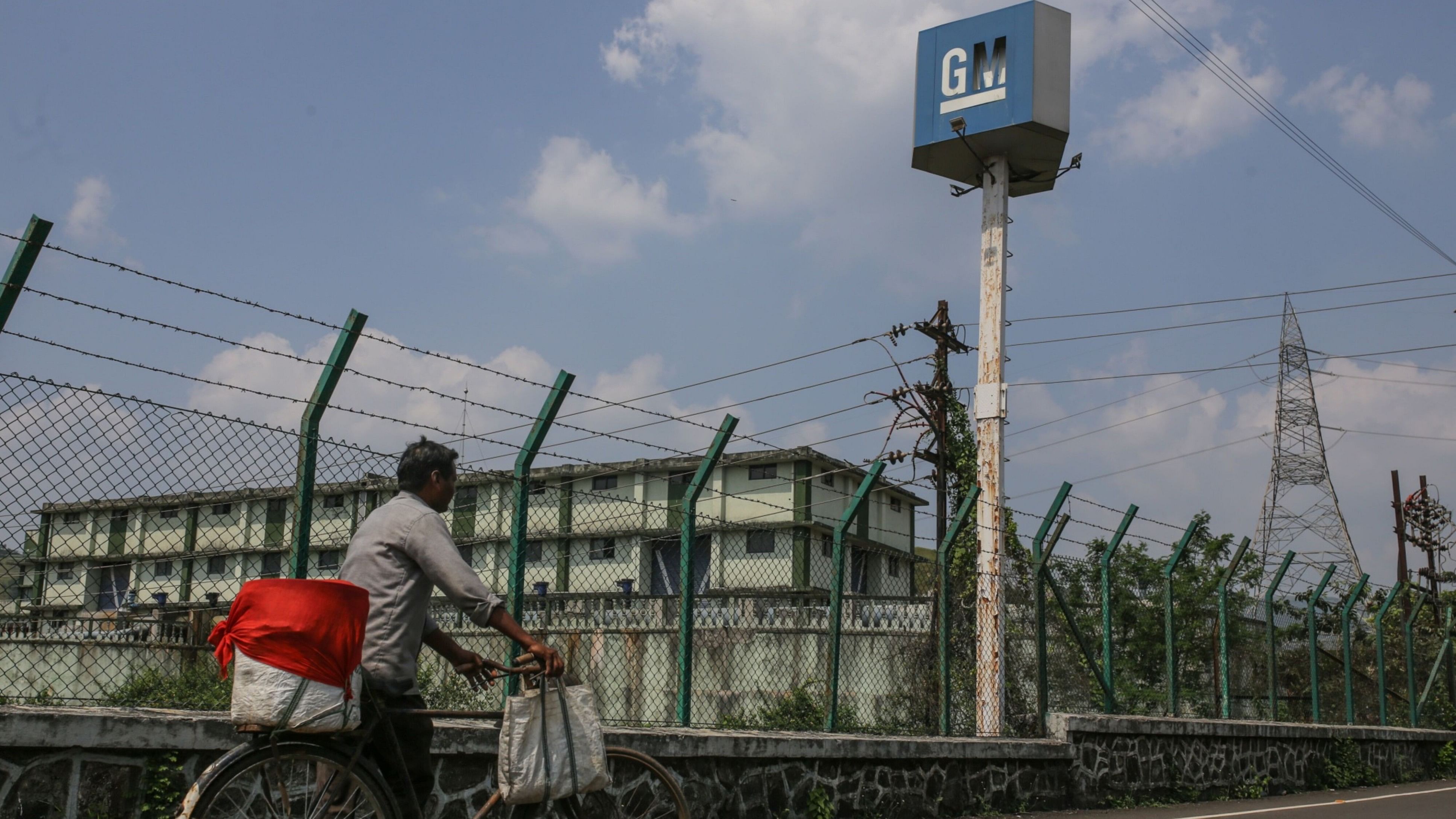 <div class="paragraphs"><p>A file photo of a pedestrian wheels a bicycle past the largely idled plant owned by General Motors Co. in Talegaon, Maharashtra.</p></div>