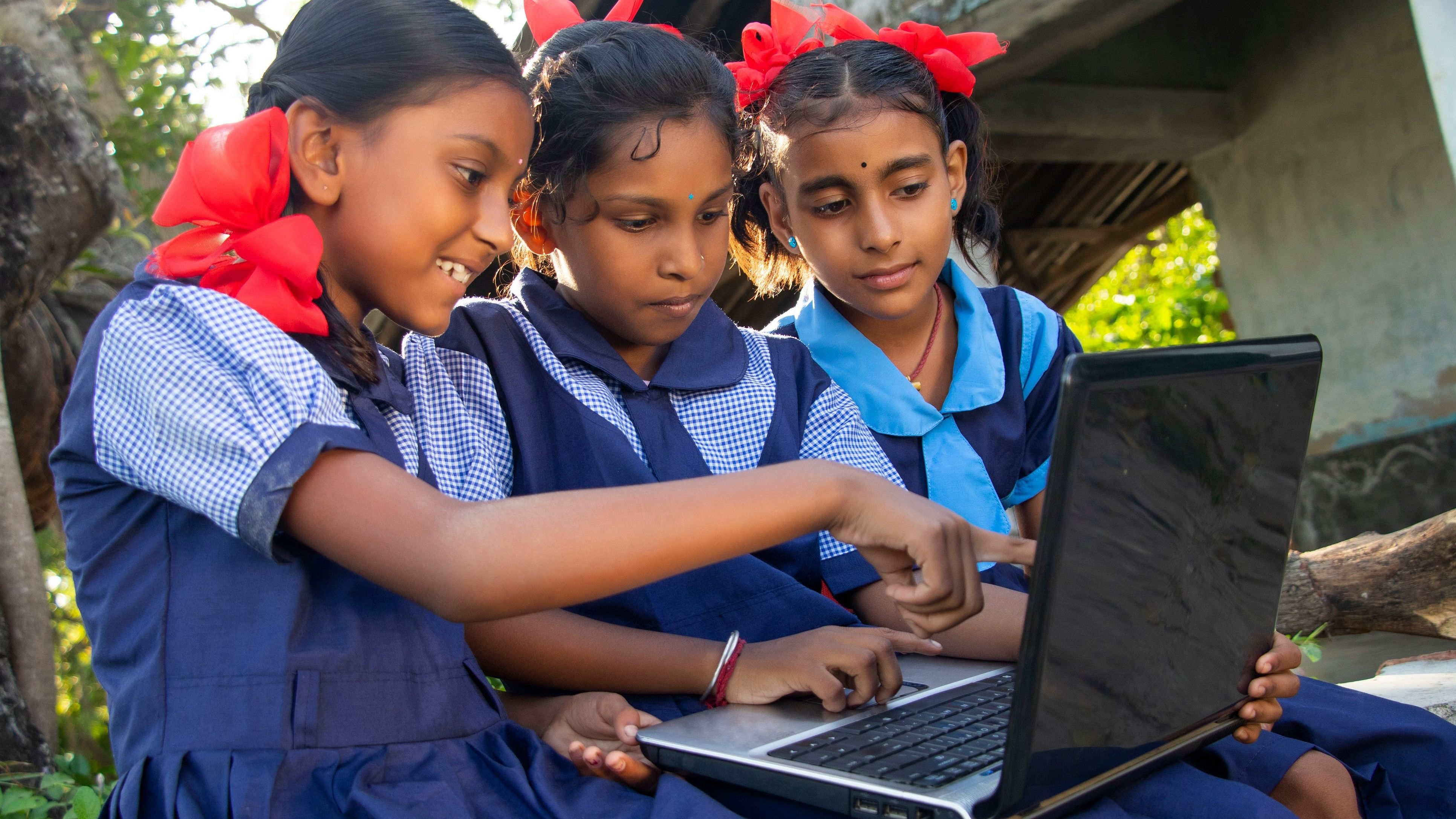 Indian village government school girls operating laptop computer systems in rural area in India