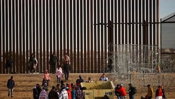 <div class="paragraphs"><p>Migrants gather near the border wall after crossing a razor wire fence deployed to inhibit their crossing into the US.</p></div>