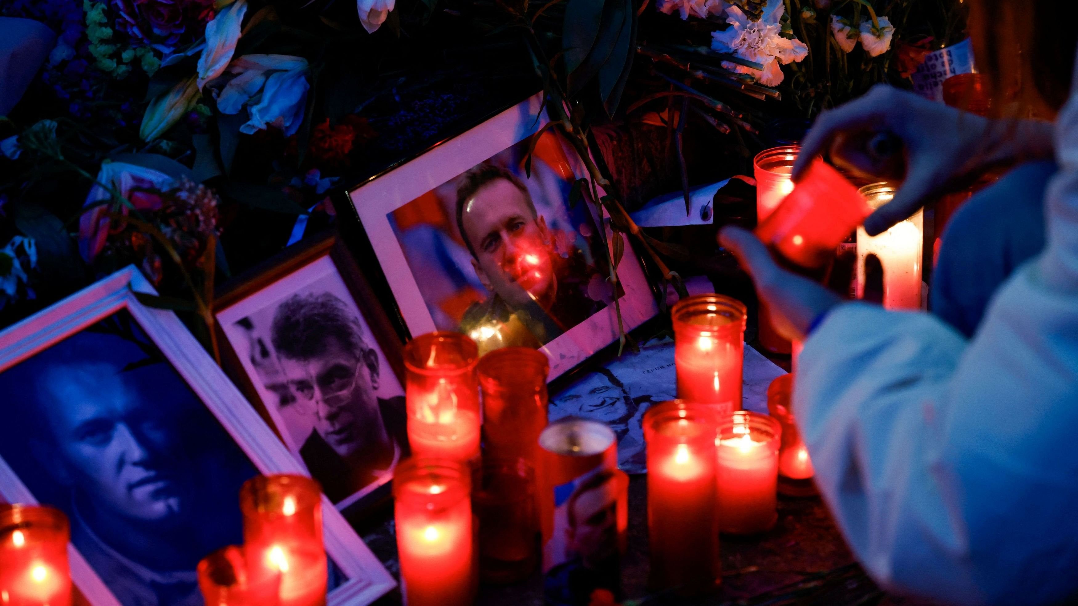 <div class="paragraphs"><p>A person holds a candle as people gather in memory of Alexei Navalny.</p></div>