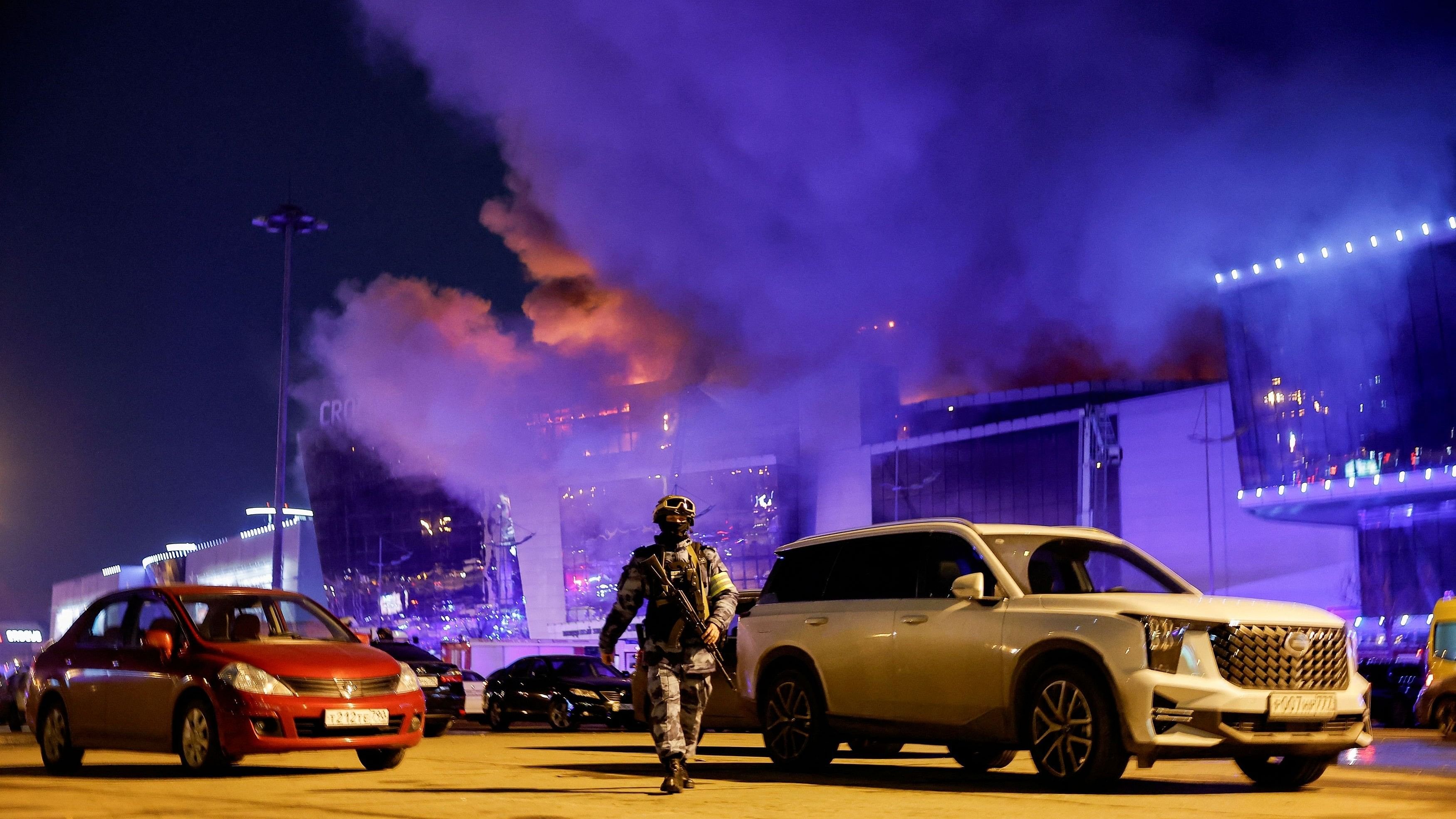 <div class="paragraphs"><p>A Russian law enforcement officer walks at a parking area near the burning Crocus City Hall concert venue following a shooting incident, outside Moscow, Russia, March 22, 2024. </p></div>