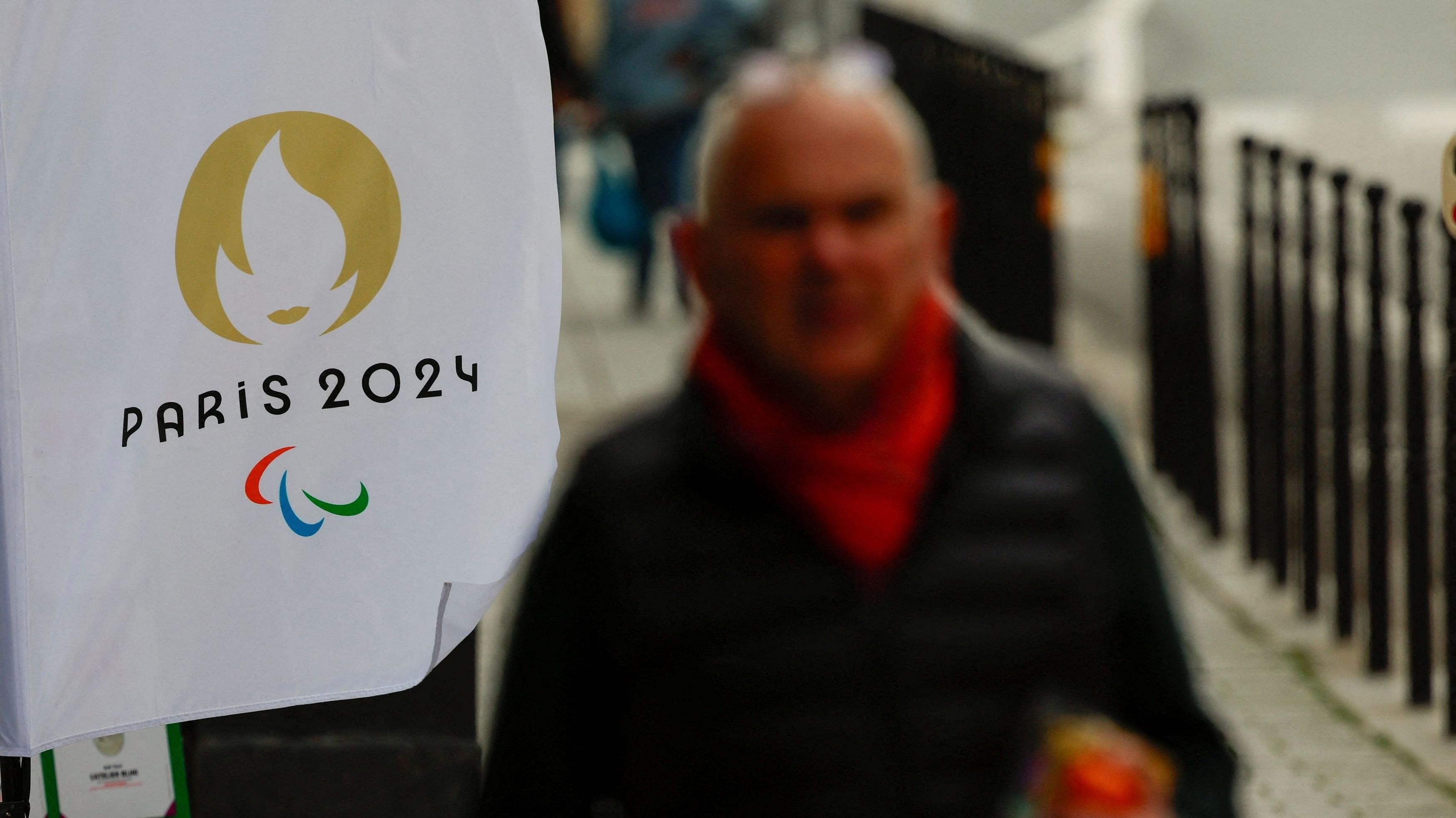 <div class="paragraphs"><p>A man walks near a flag with the logo of the Paris 2024 Olympic and Paralympic Games in Paris, France, March 25, 2024. </p></div>