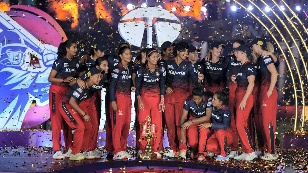 <div class="paragraphs"><p>Royal Challengers Bangalore players pose with the trophy after winning the WPL-T20 final cricket match.</p></div>