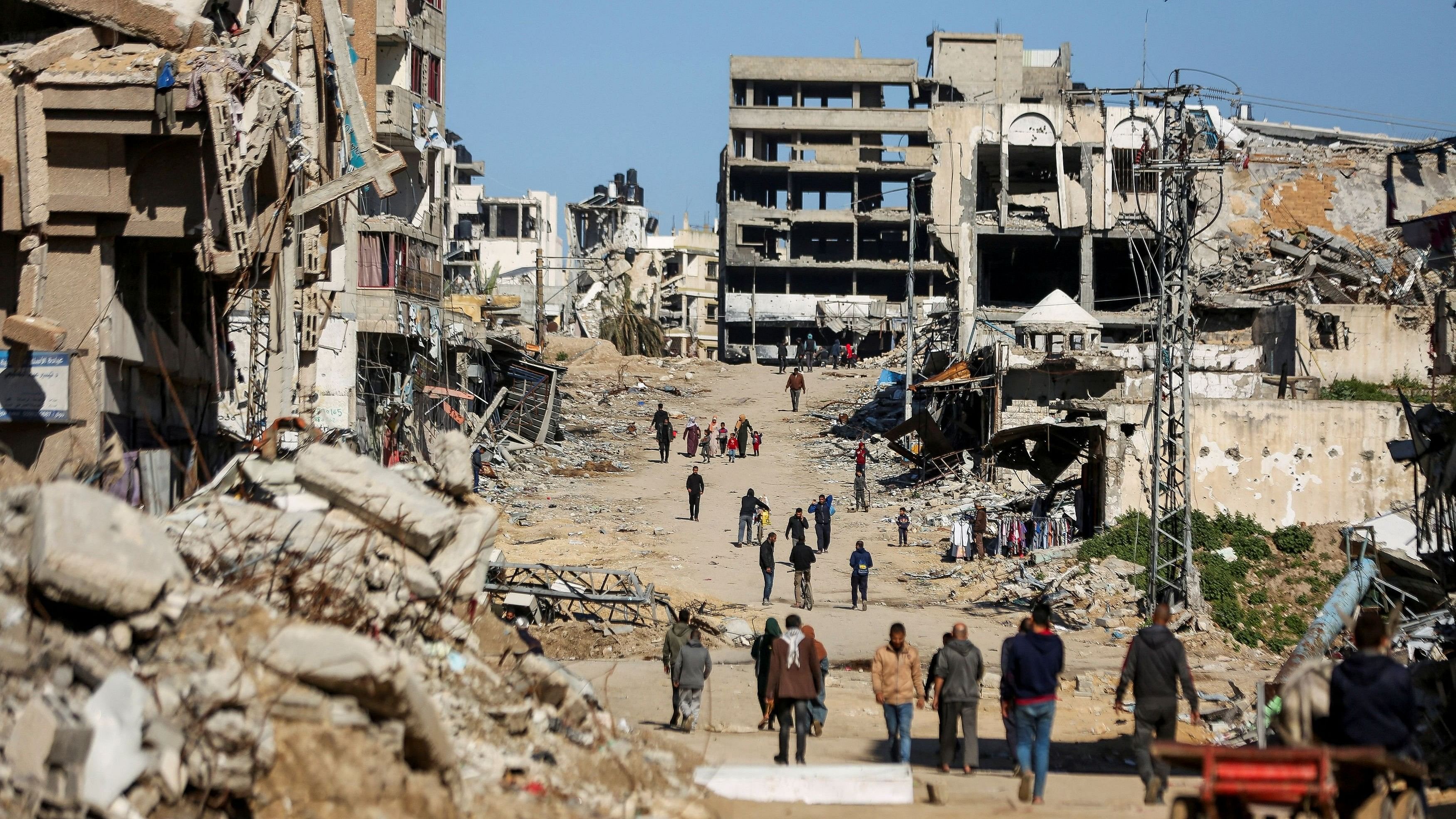 <div class="paragraphs"><p>Palestinians walk past the ruins of houses destroyed during Israel's military offensive, amid the ongoing conflict between Israel and Hamas, in Gaza City.</p></div>