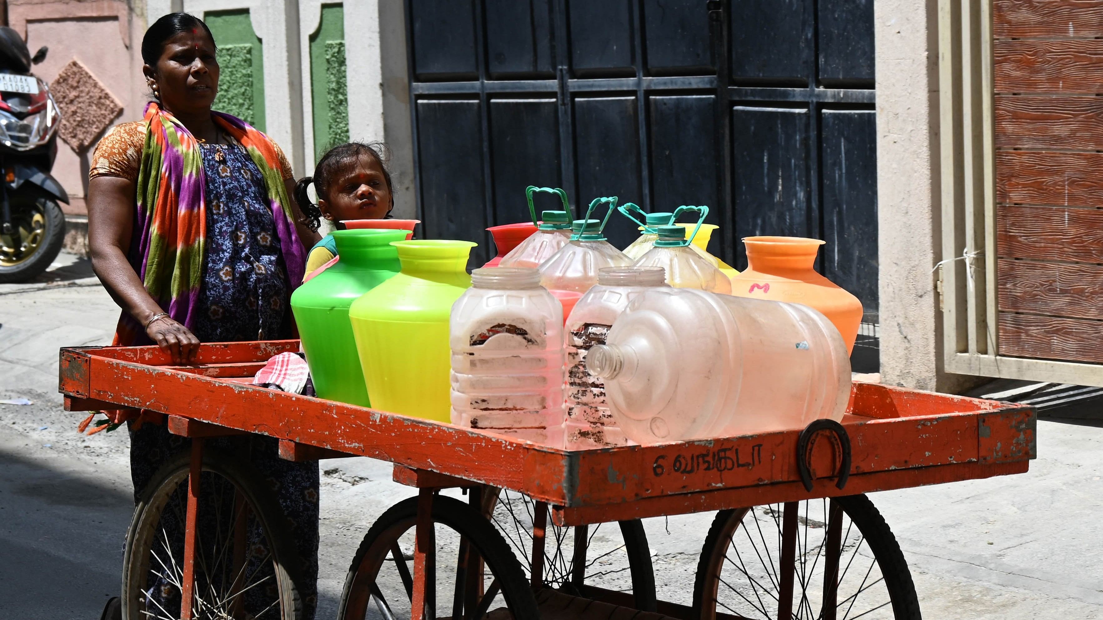 <div class="paragraphs"><p>A woman and her child push a cart with empty water cans meant for refilling,at Benson Town in Bengaluru.&nbsp;</p></div>