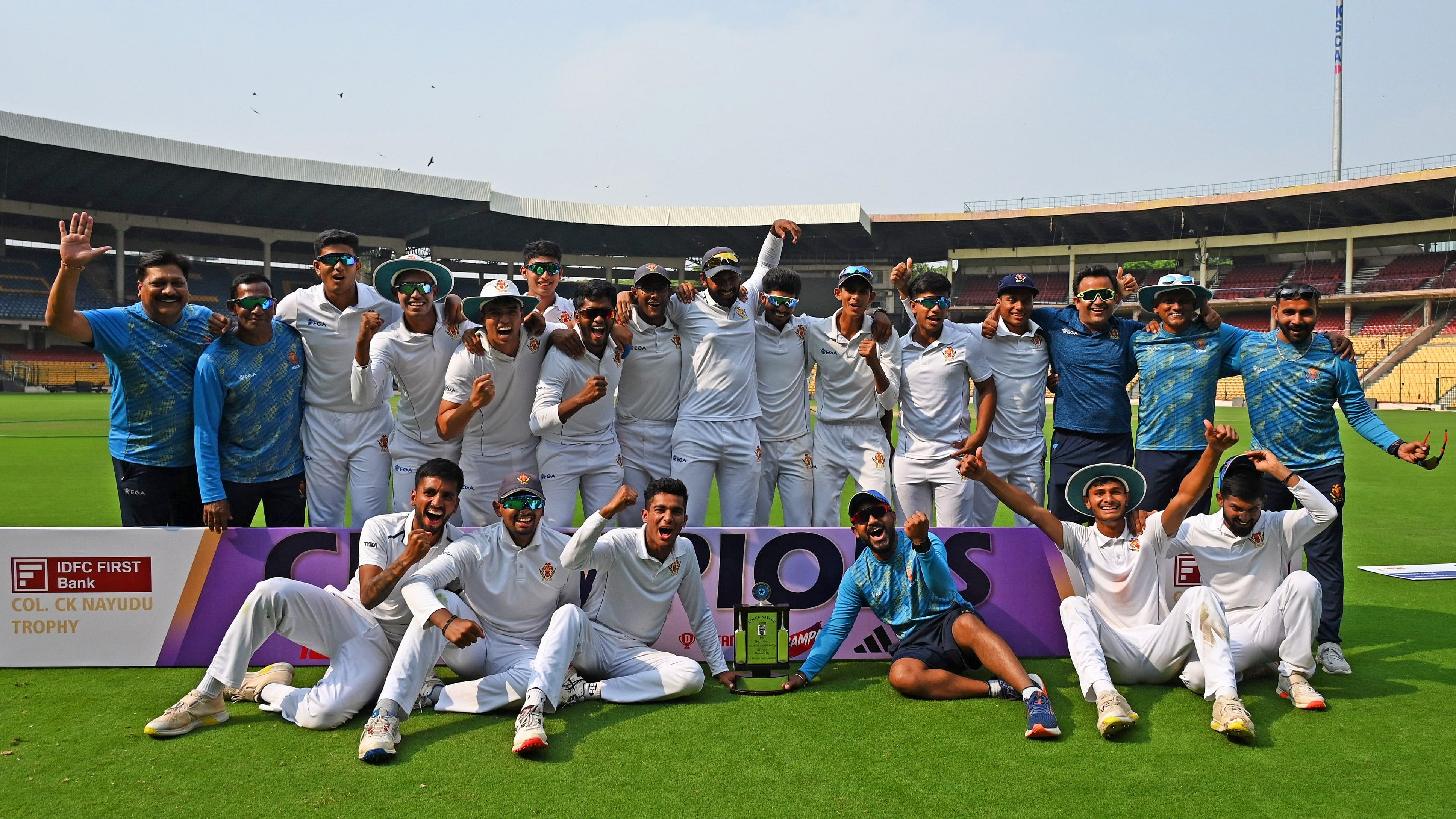 <div class="paragraphs"><p>Karnataka team members celebrate after claiming their maiden Col CK Nayudu Trophy at the M Chinnaswamy Stadium in Bengaluru on Wednesday. </p></div>