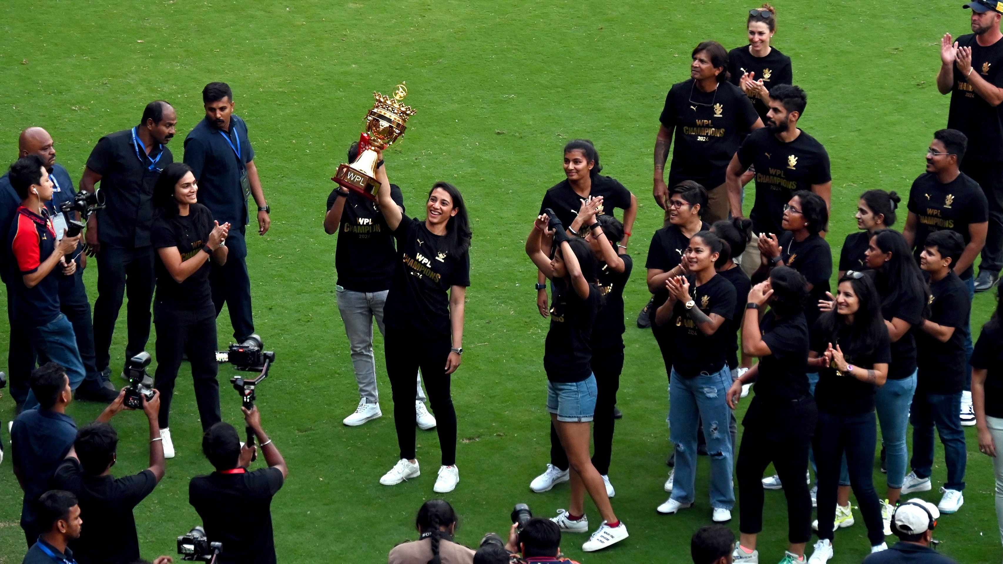 <div class="paragraphs"><p>Royal Challengers Bengaluru captain Smriti Mandhana hoists the trophy while the rest of her teammates look on during a lap of honour during the RCB Unbox Event 2024 at the M Chinnaswamy Stadium in Bengaluru on Tuesday</p></div>