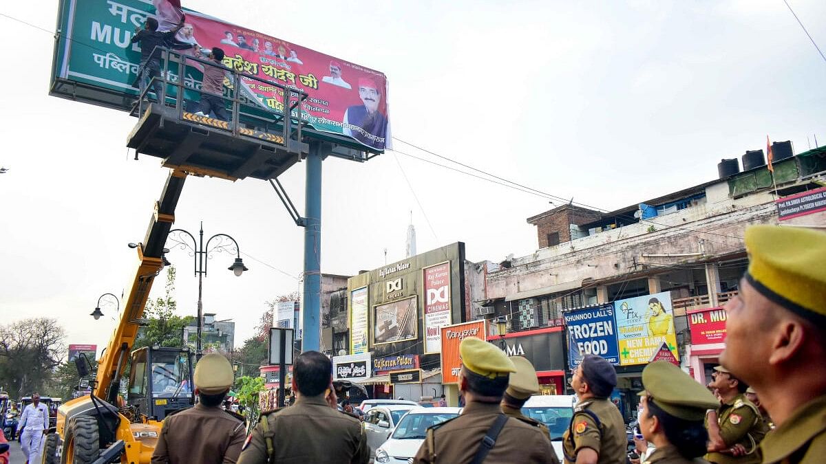 <div class="paragraphs"><p> Workers remove posters of political leaders after the Model Code of Conduct was enforced following the announcement of the schedule of Lok Sabha elections, in Prayagraj as police personnel look on.</p></div>