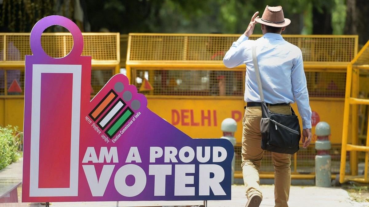 <div class="paragraphs"><p>File photo of a man walking past a photo point installed at the Election Commission of India's headquarter in New Delhi.</p></div>