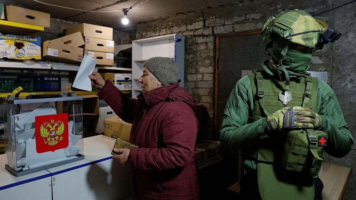 <div class="paragraphs"><p>A local resident casts her vote into a mobile ballot box next to a security member during the Russia's presidential election, in the basement of a destroyed apartment building in the course of Russia-Ukraine conflict in the town of Avdiivka in the Donetsk Region, Russian-controlled Ukraine, March 16, 2024.</p></div>