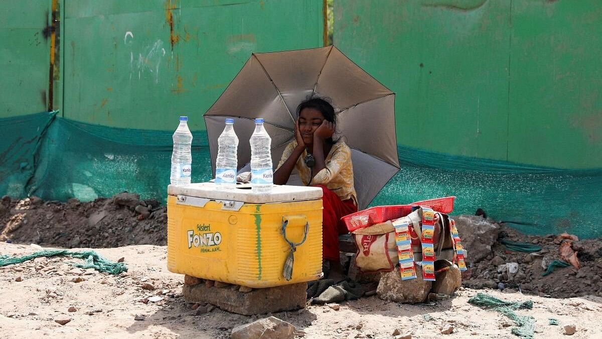 <div class="paragraphs"><p>A girl selling water uses an umbrella to protect herself from the sun as she waits for customers on a hot summer day, in New Delhi.&nbsp;</p></div>