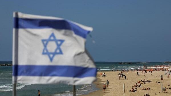 <div class="paragraphs"><p>An Israeli flag flutters as people rest on the beach, after Iran launched drones and missiles towards Israel, in Tel Aviv, Israel, April 14, 2024. </p></div>