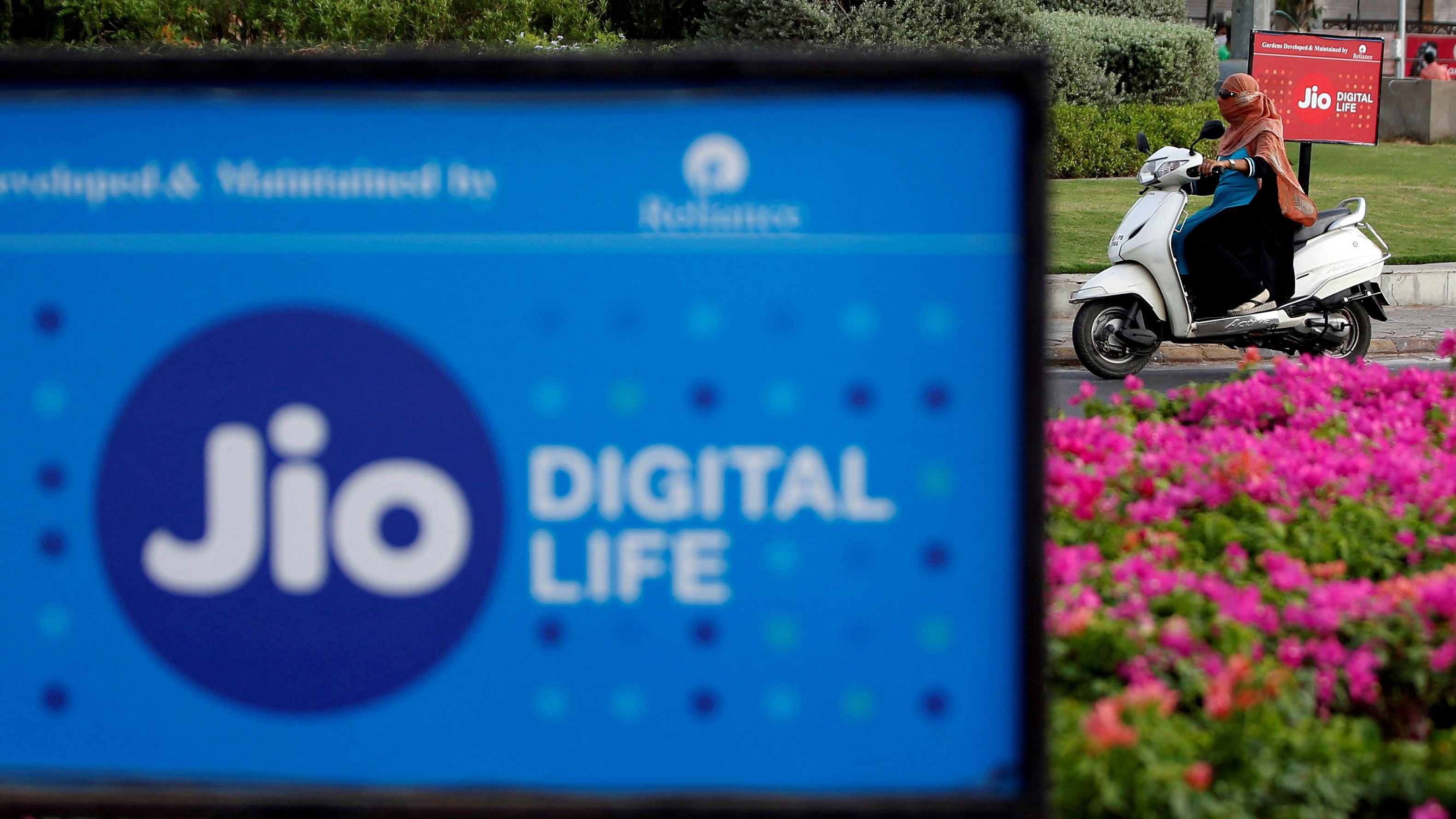 <div class="paragraphs"><p>A woman rides her scooter past a Reliance Industries' Jio telecoms unit, India.</p></div>