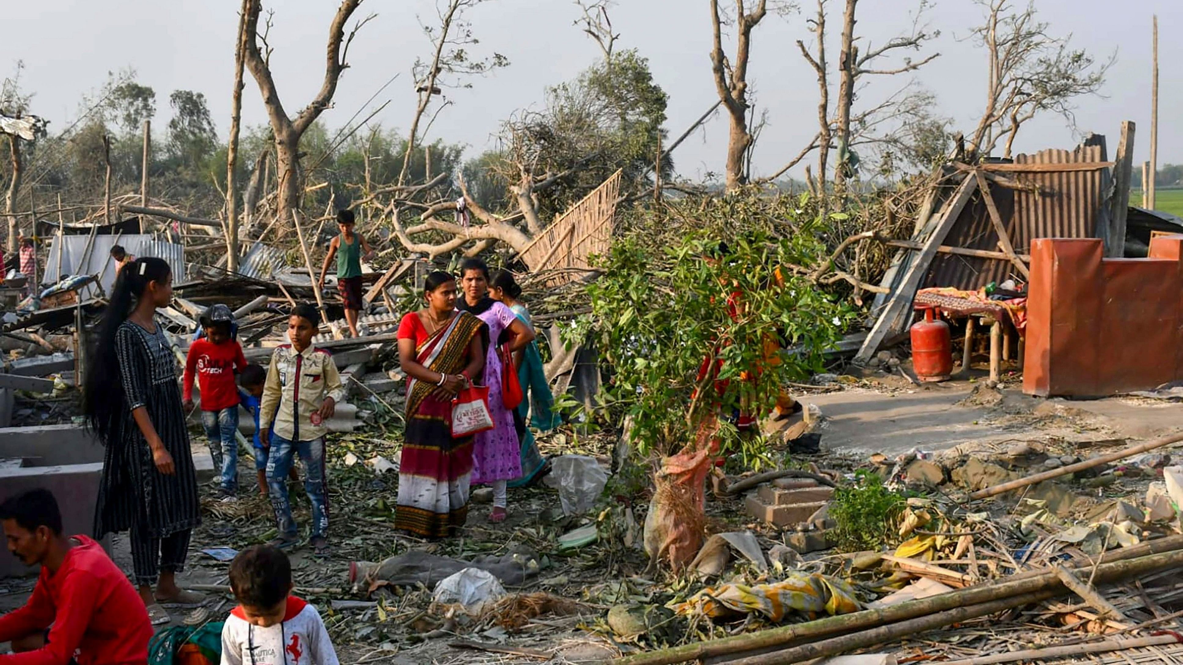 <div class="paragraphs"><p>Villagers stand near damaged houses after the recent storm in Jalpaiguri district.</p></div>