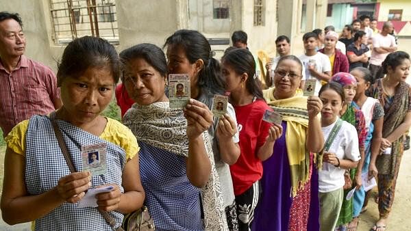 <div class="paragraphs"><p>Voters show their identification cards as they wait in a queue at a polling station to cast their votes for the first phase of Lok Sabha elections, in Ri Bhoi district, Friday, April 19, 2024.</p></div>