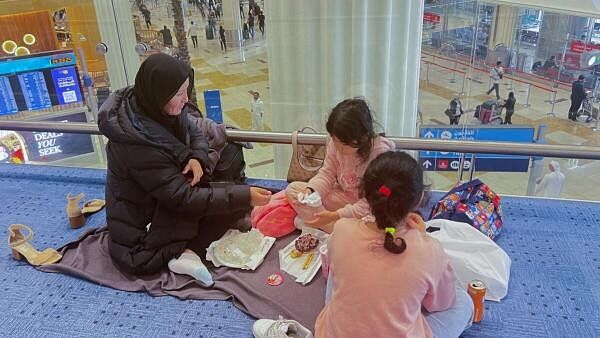 <div class="paragraphs"><p>A woman and her daughters eat as they wait for their flight after a rainstorm hit Dubai, causing delays at Dubai International Airport, United Arab Emirates, April 17, 2024. </p></div>