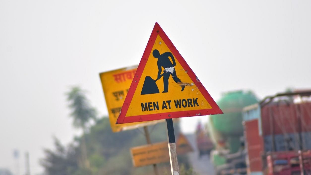 <div class="paragraphs"><p>A closeup shot of a road sign with men at work on it.</p></div>