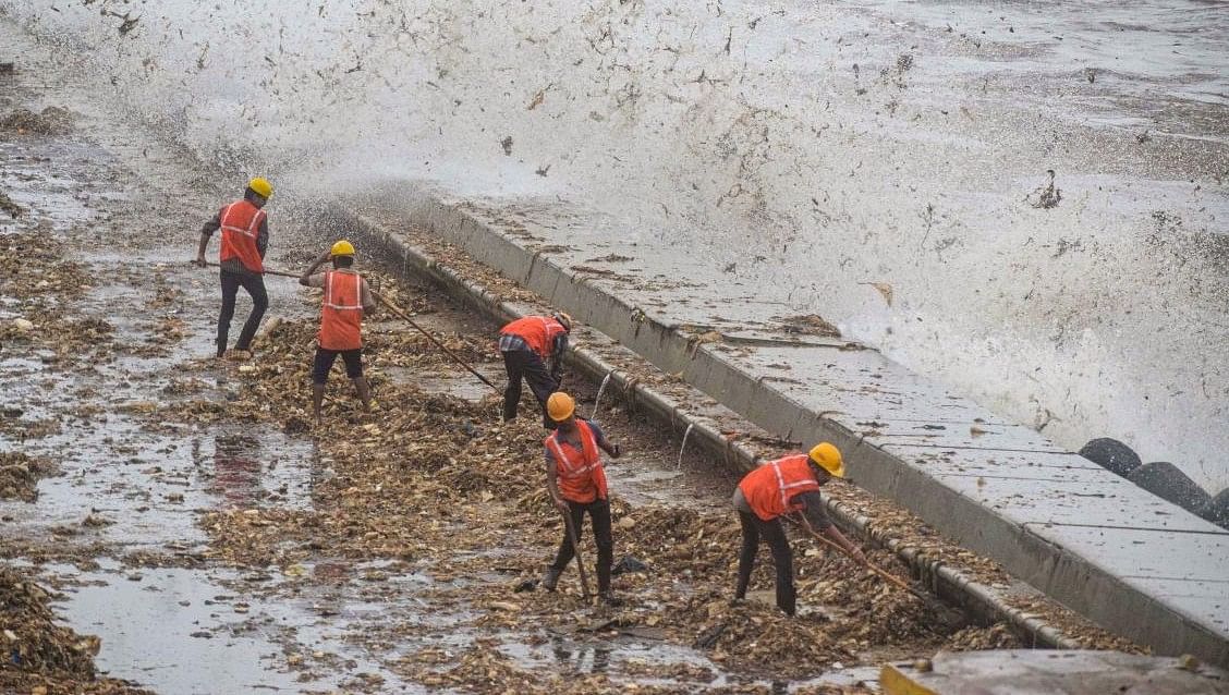 <div class="paragraphs"><p>Brihanmumbai Municipal Corporation (BMC) workers clear the garbage washed ashore during high tide, on the promenade along the Marine Drive, in Mumbai, Saturday, Aug 3, 2019.</p></div>