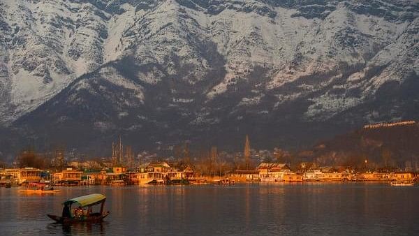 <div class="paragraphs"><p>A boatman rows his shikara at Dal Lake in Srinagar during sunset as snow covers the ranges in background. </p></div>