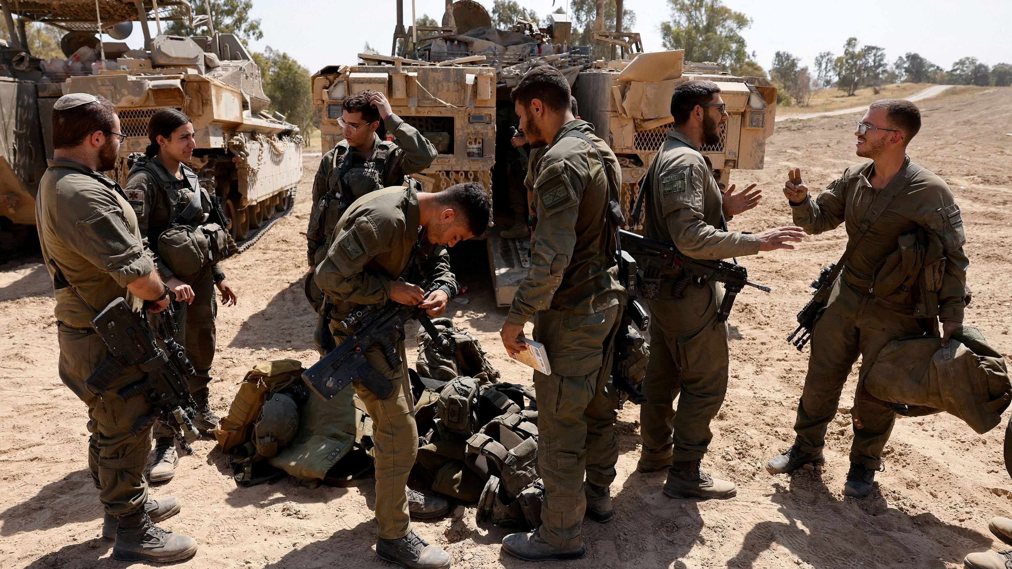 <div class="paragraphs"><p>Israeli soldiers stand next to military vehicles, near the Israel-Gaza border.</p></div>