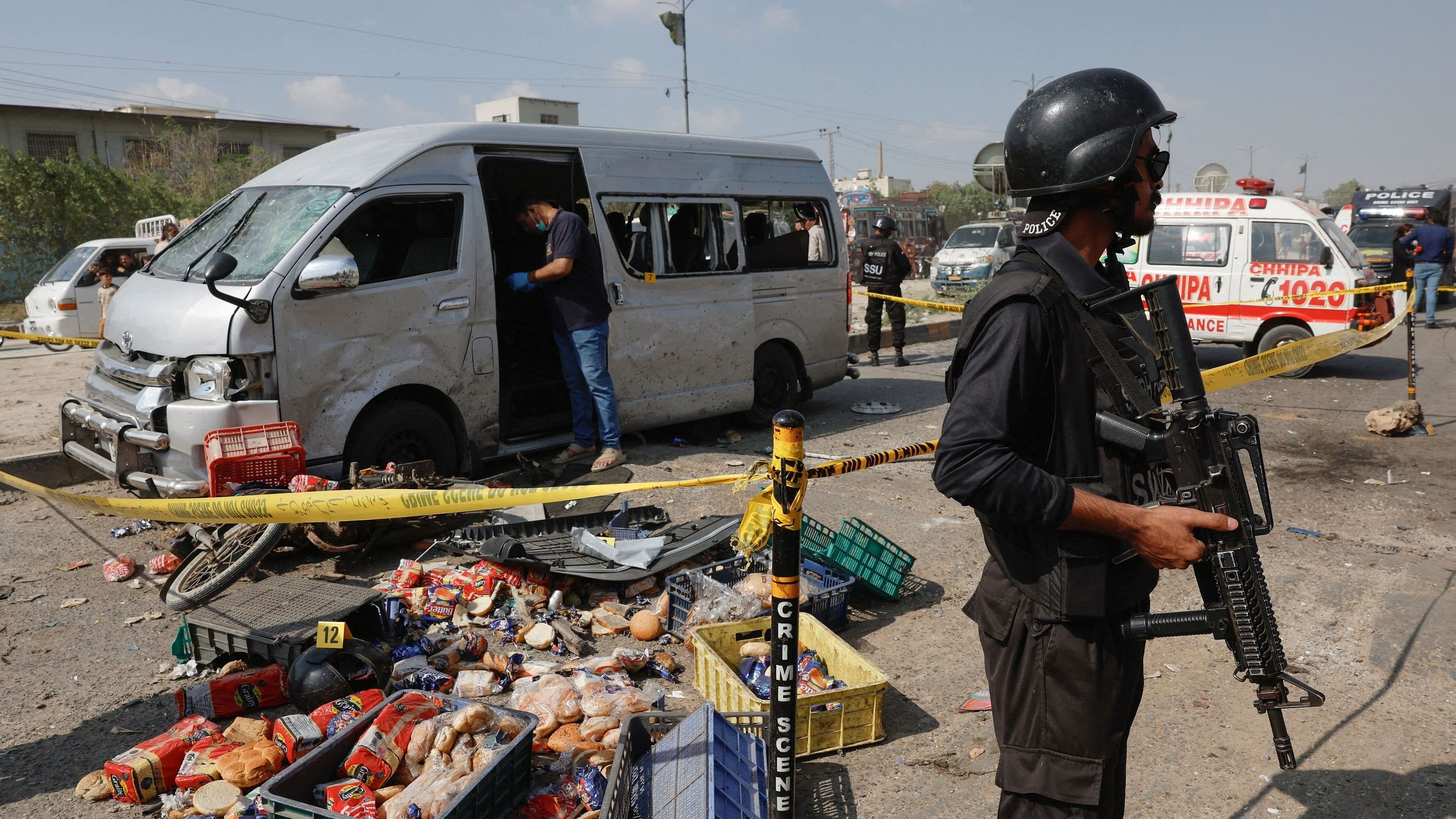 A police officer stands guard near a cordoned damaged vehicle after a suicide blast in Karachi, Pakistan April 19, 2024. REUTERS/Akhtar Soomro