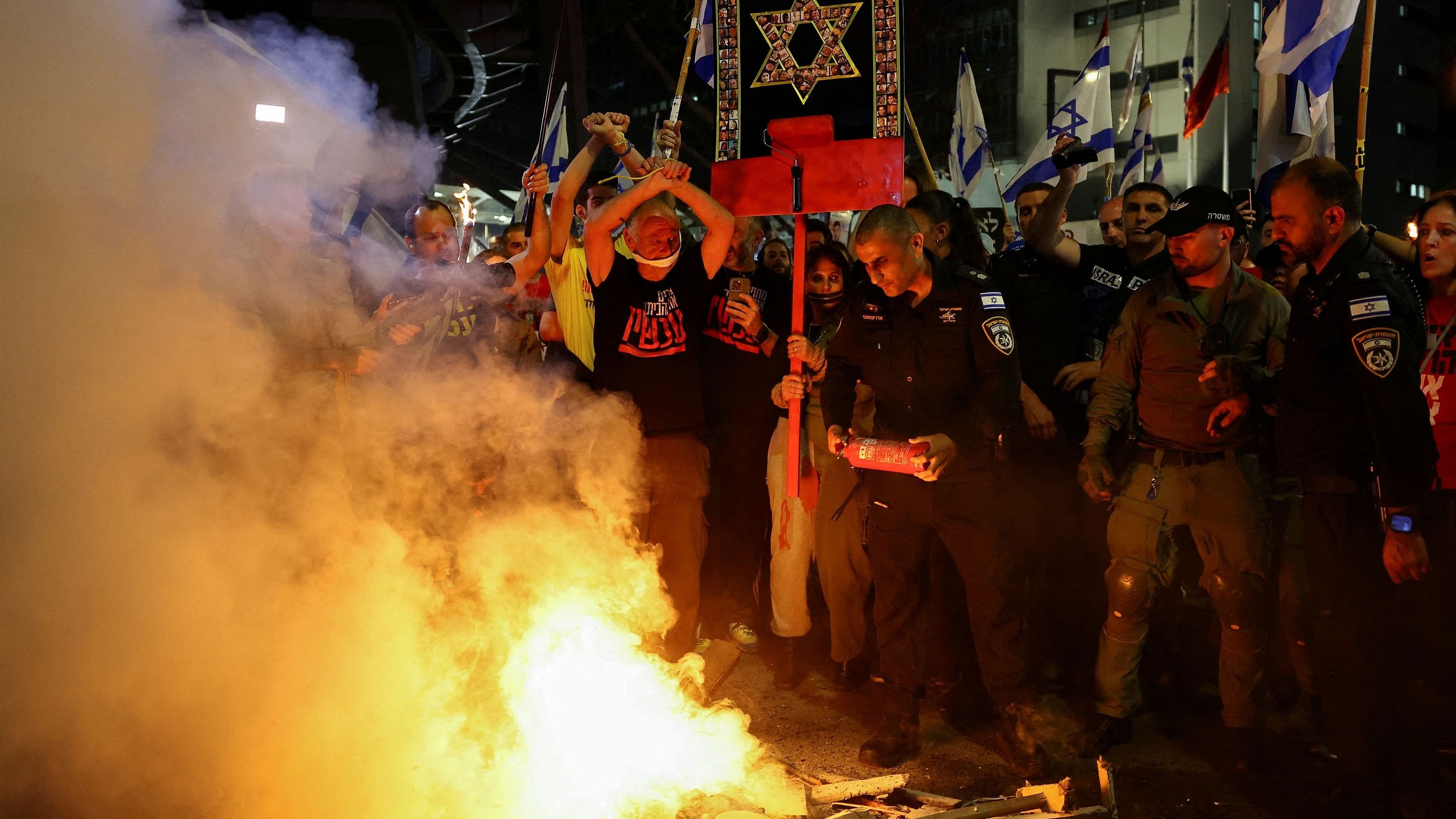 <div class="paragraphs"><p>A police officer holds a fire extinguisher as people protest against Israeli Prime Minister Benjamin Netanyahu's government and call for the release of hostages kidnapped in the deadly October 7 attack on Israel by the Palestinian Islamist group Hamas from Gaza, in Tel Aviv, Israel.</p></div>