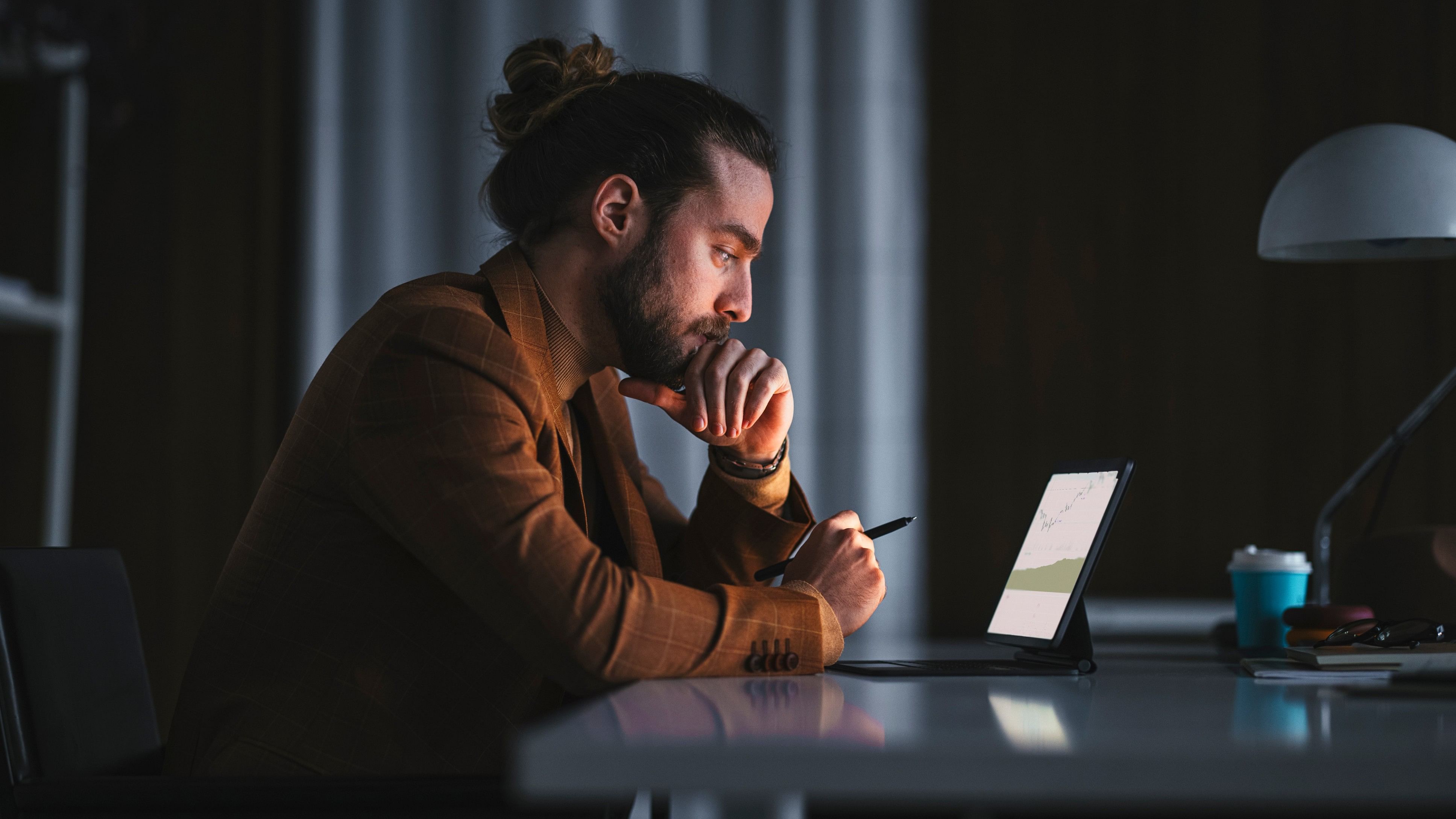 <div class="paragraphs"><p>Side view of serious thoughtful adult bearded male in stylish wear sitting at table with modern laptop and analyzing business information while working in office in late evening Pensive man working on laptop in office.</p></div>