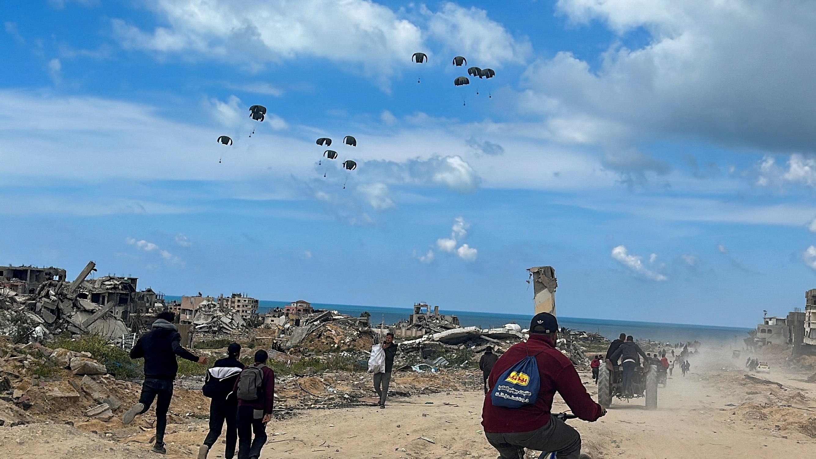 <div class="paragraphs"><p>Palestinians rush towards the beach to collect aid airdropped by an airplane, amid the ongoing war between Israel and Hamas, in the northern Gaza Strip, March 25, 2024.</p></div>