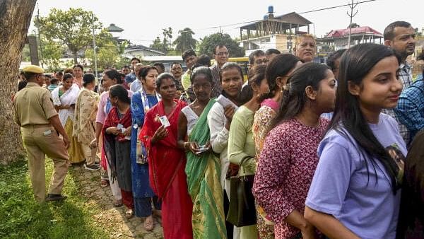 <div class="paragraphs"><p>Voters wait in a queue at a polling station to cast their votes for the first phase of Lok Sabha elections, in Jorhat district, Friday, April 19, 2024.</p></div>