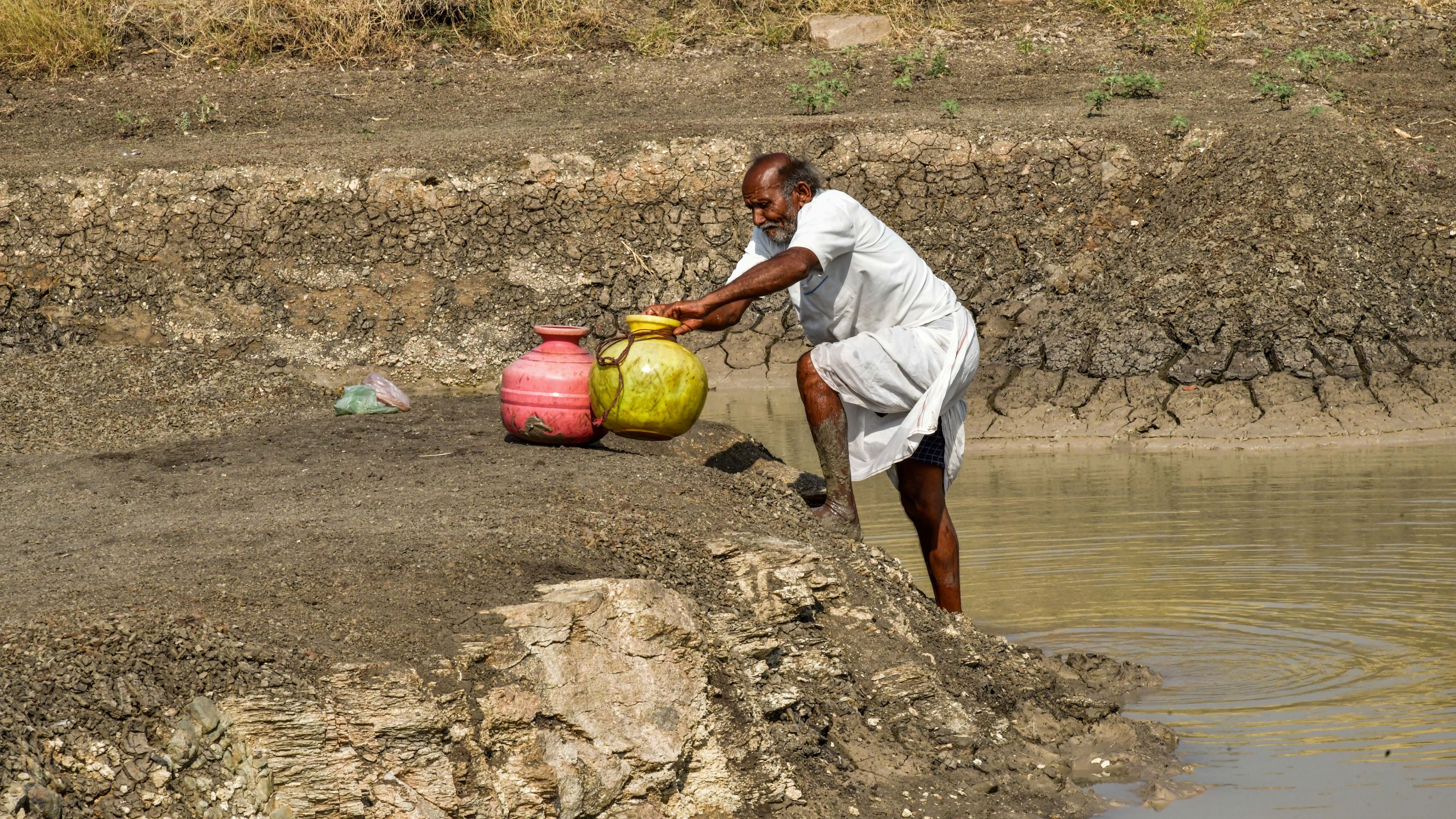 Residents fill their pots with water from an almost-dry tank at Kavalur villageof Koppal taluk.DH PHOTO/BHARATH KANDAKUR. 