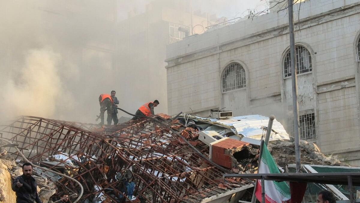 <div class="paragraphs"><p>Members of the civil defence stand near a damaged site after what Syrian and Iranian media described as an Israeli air strike on Iran's consulate in the Syrian capital Damascus.</p></div>