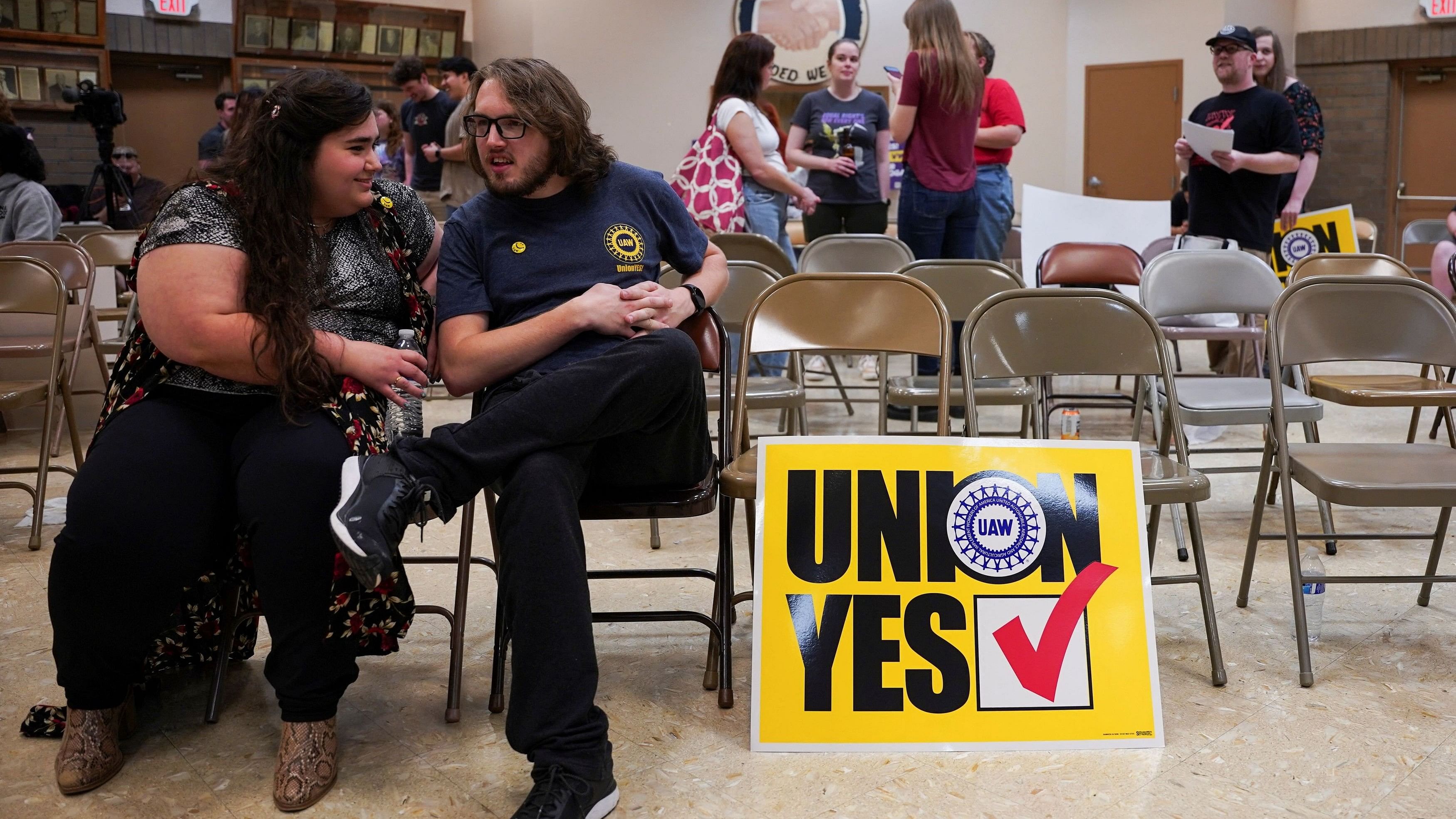 <div class="paragraphs"><p>People sit next to a placard that says 'Union Yes' as the result of a vote comes in favour of the hourly factory workers at Volkswagen's assembly plant to join the United Auto Workers  union, during a watch party in Chattanooga, Tennessee.</p></div>