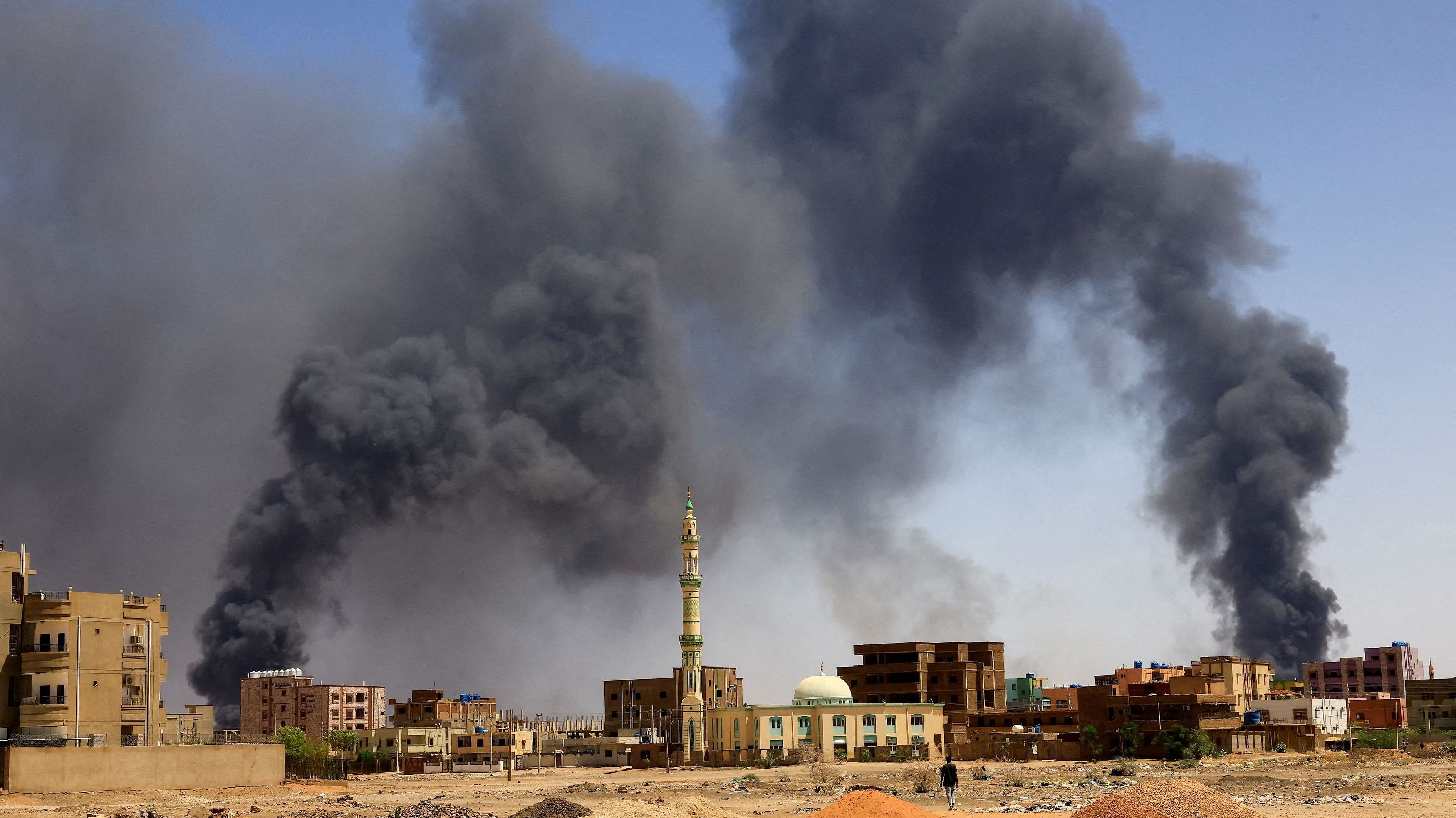 <div class="paragraphs"><p>A man walks while smoke rises above buildings  in Khartoum North, Sudan.</p></div>
