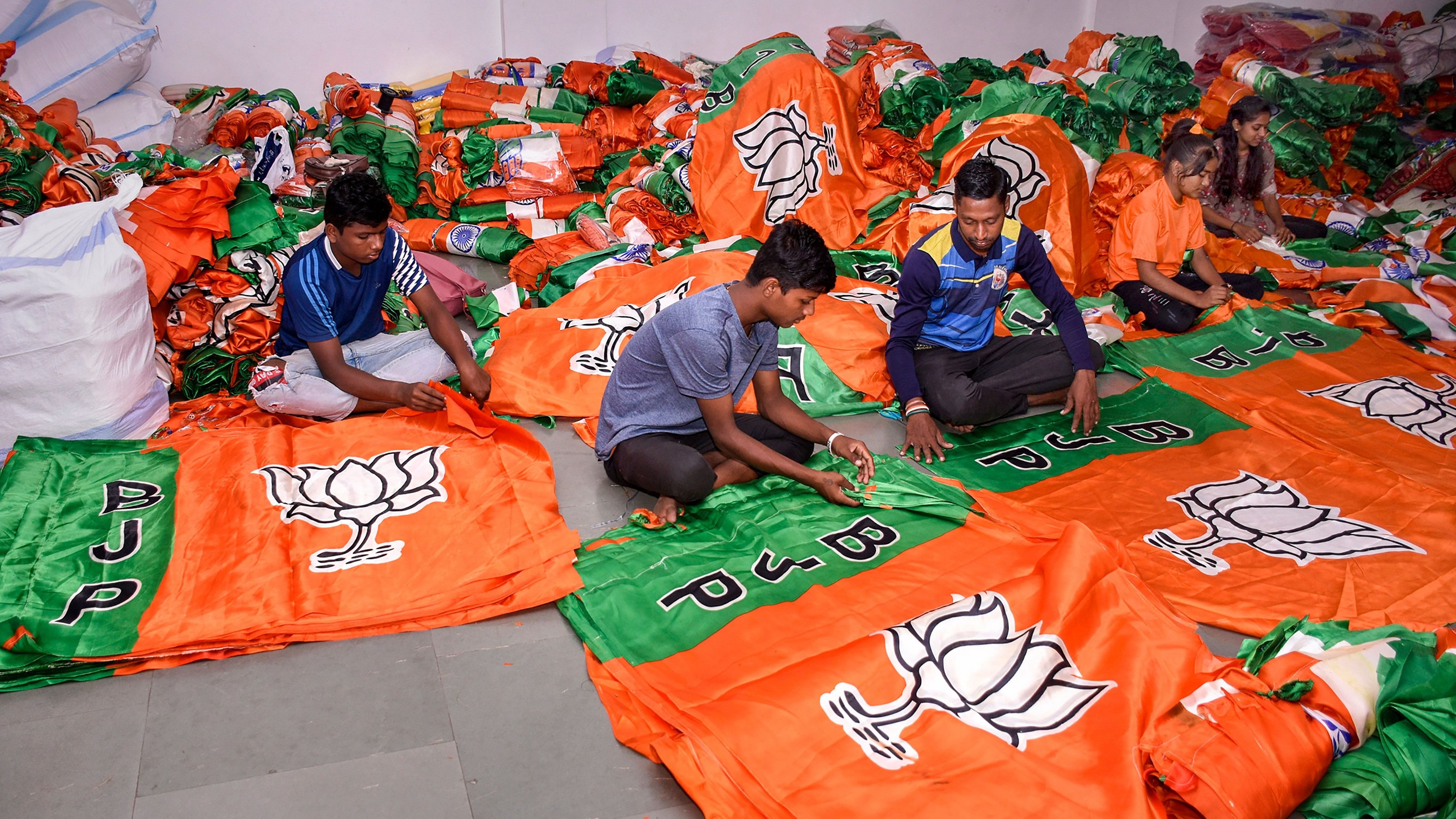 <div class="paragraphs"><p>Workers prepare BJP party flags in Surat. </p></div>