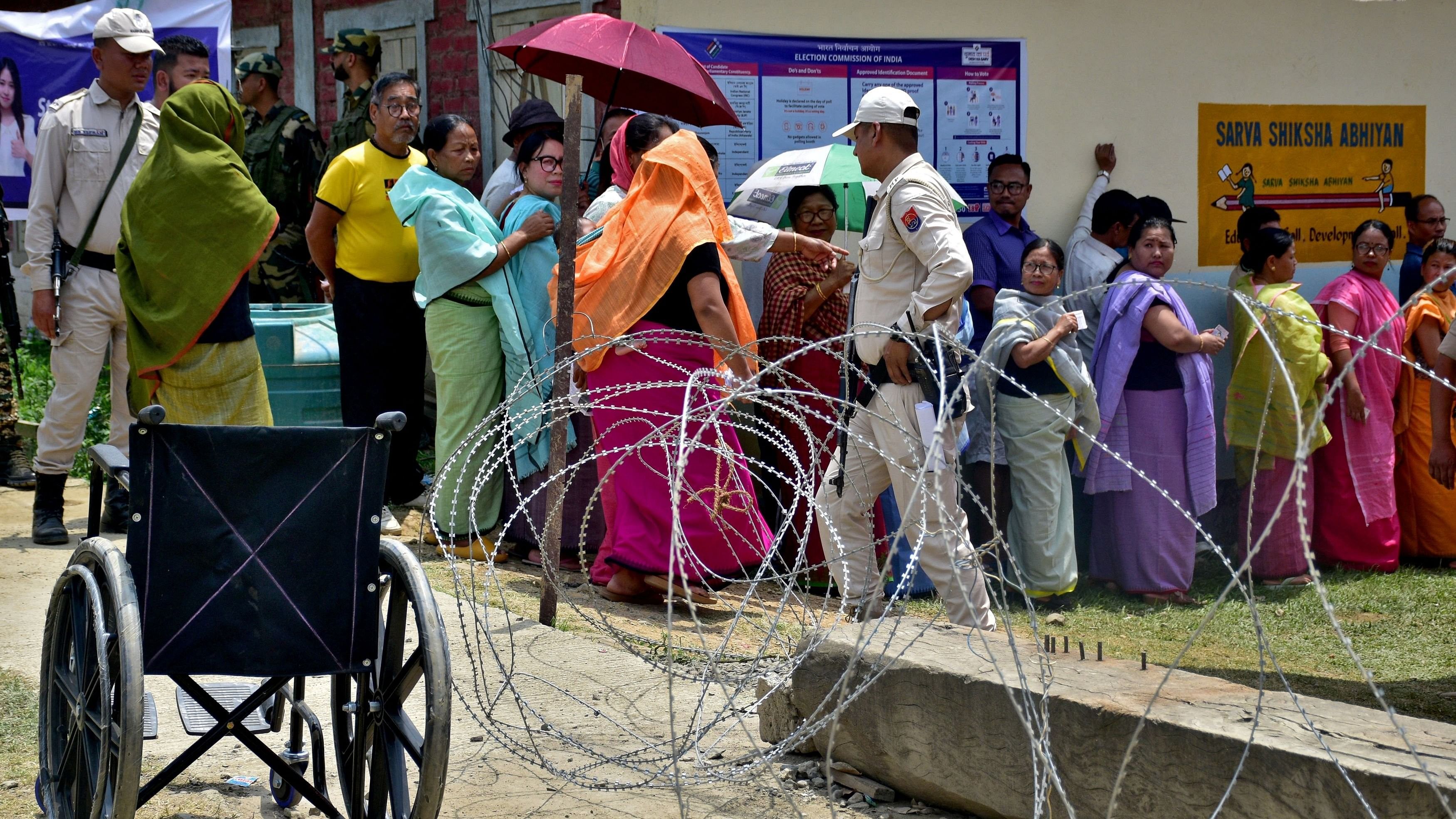 <div class="paragraphs"><p>Police officers stand guard as voters wait in lines to cast their votes at a polling station during a rerun voting at 11 polling stations, in Imphal, Manipur.</p></div>