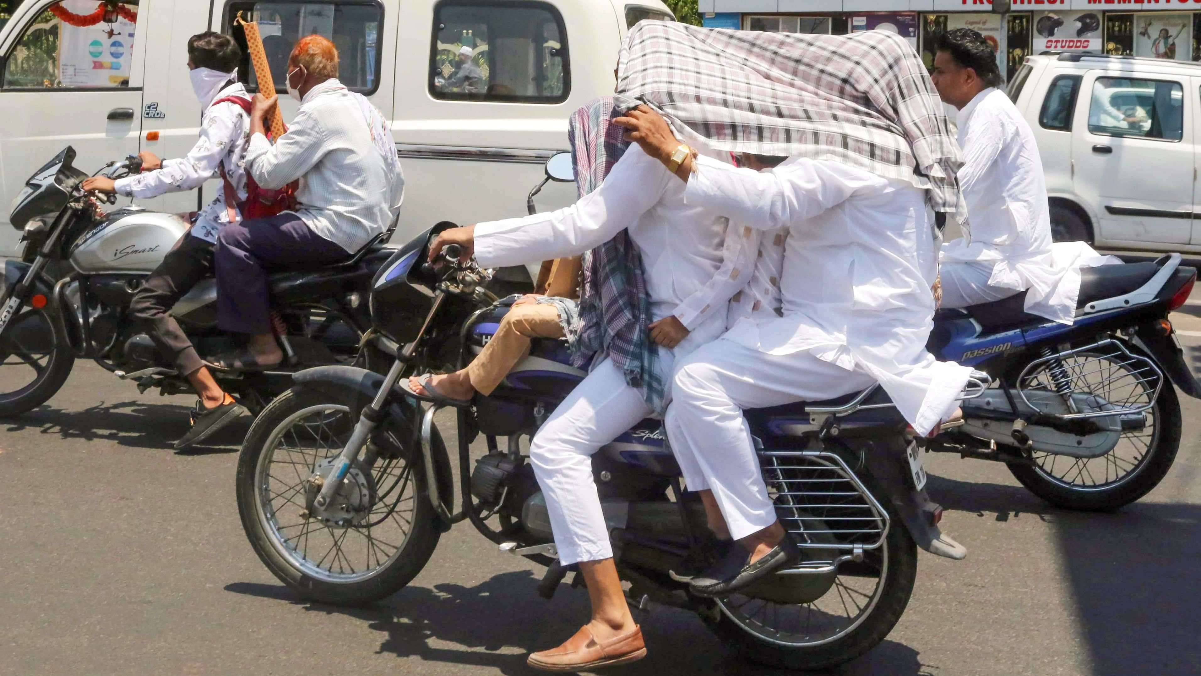 <div class="paragraphs"><p>Motorists use a piece of cloth to shield themselves from the sun, on a hot summer day, in Bhopal.</p></div>