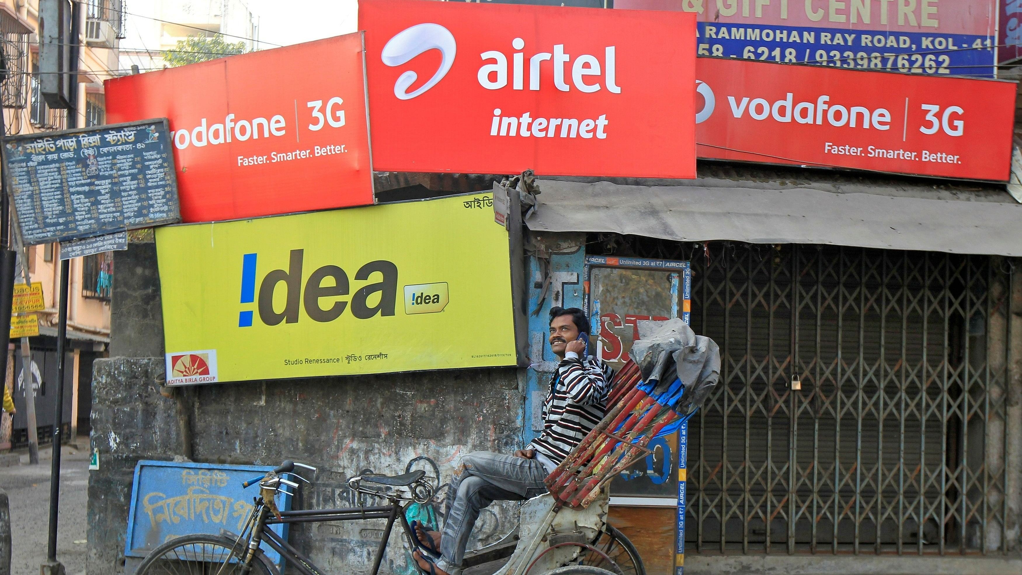 <div class="paragraphs"><p>A rickshaw puller speaks on his mobile phone as he waits for customers in front of advertisement billboards belonging to telecom companies in Kolkata, India.</p></div>