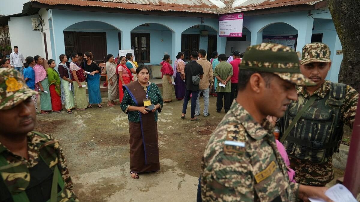 <div class="paragraphs"><p>Voters queue as they wait to cast their votes next to security force personnel outside a polling station during the first phase of the general election, in Imphal, Manipur, India, April 19, 2024.</p></div>