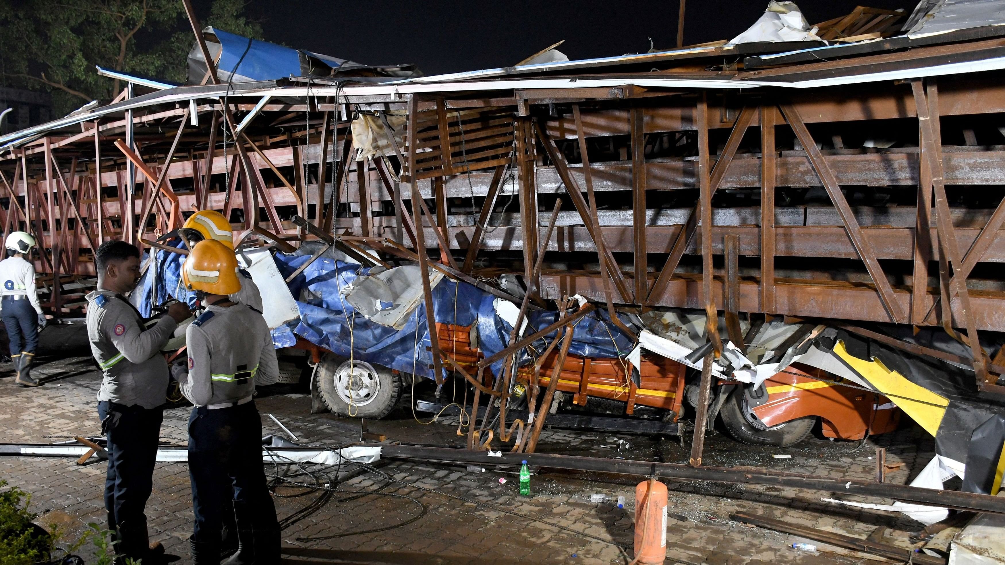 <div class="paragraphs"><p>Firefighters stand next to the damaged vehicles trapped in the debris after a massive billboard fell during a rainstorm in Mumbai, India, May 13, 2024. </p></div>